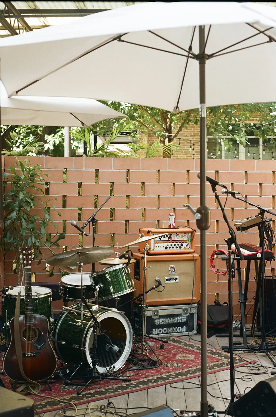 Drums, a keyboard, and amps set up for a performance at the Carpenter Hotel pool