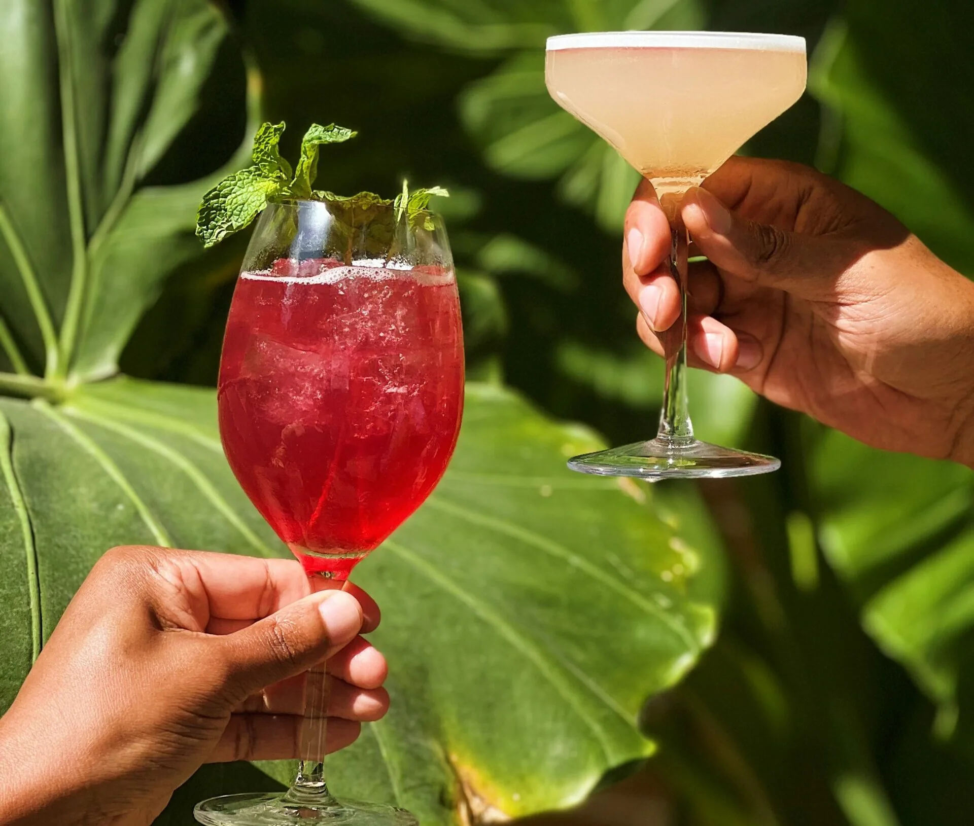 Hands holding two different cocktails
