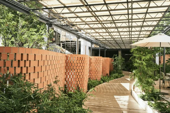 An undulating brick wall surrounded by greenery