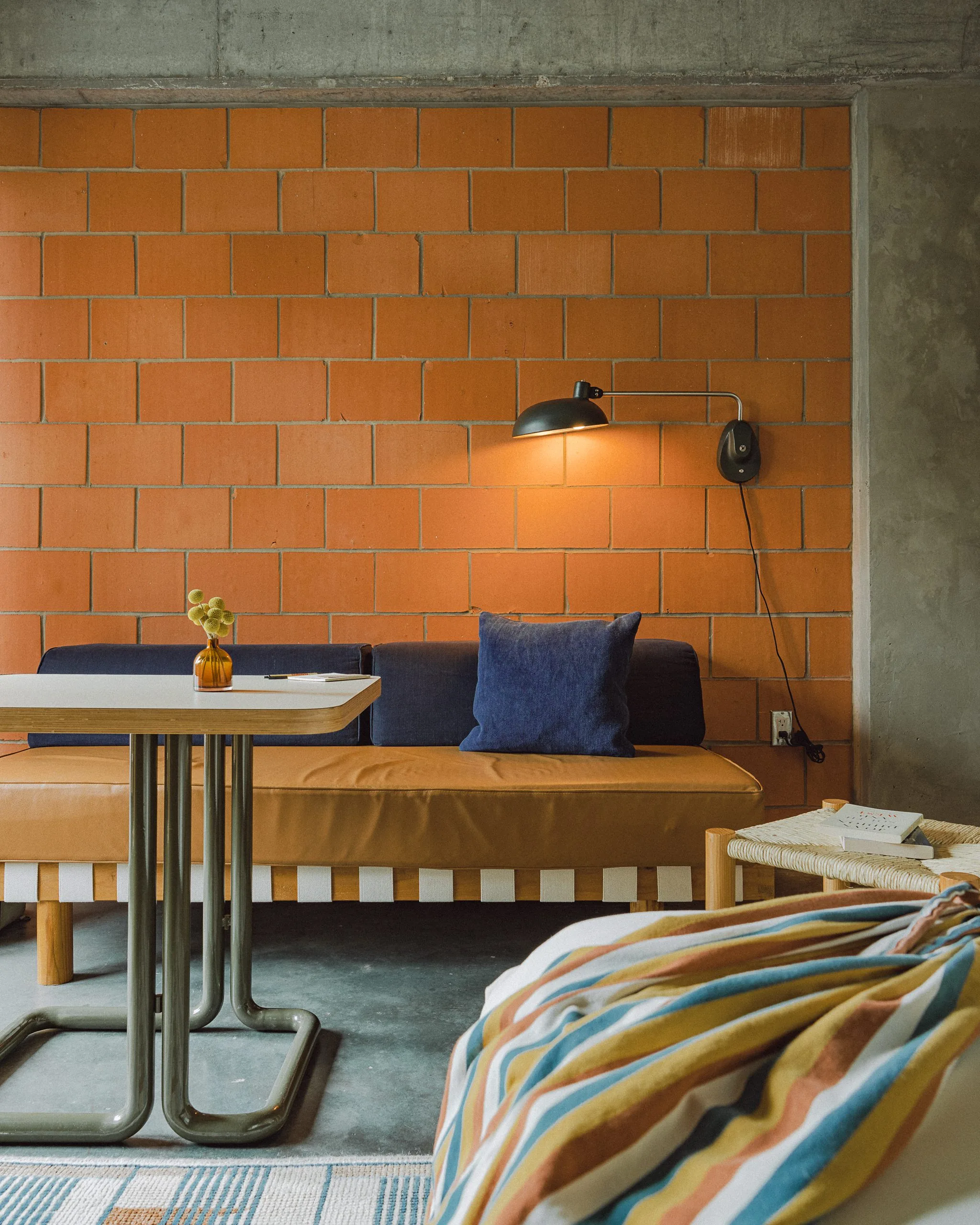 A couch and wall light against an orange bricked wall