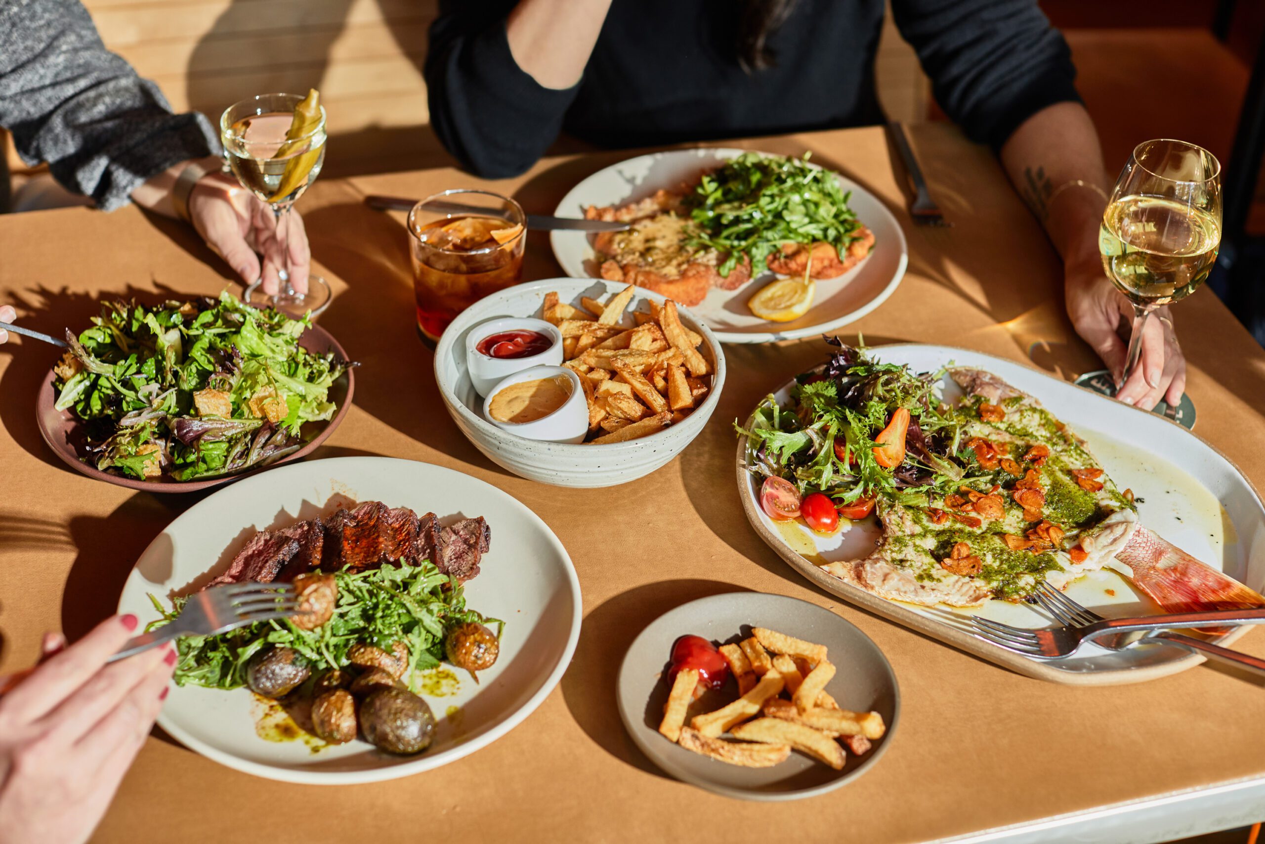 Three guests enjoying drinks and various dishes from Carpenters Hall