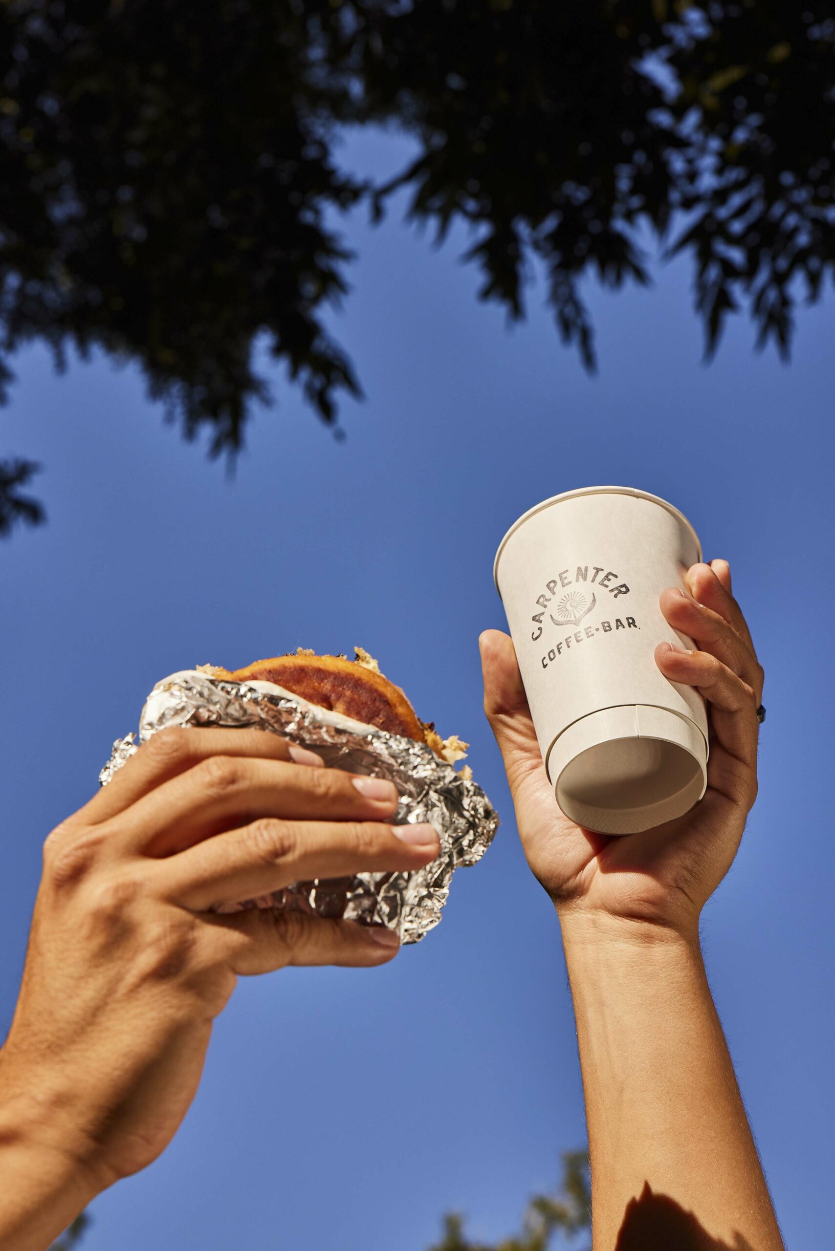 Hands holding up a coffee cup and sandwich
