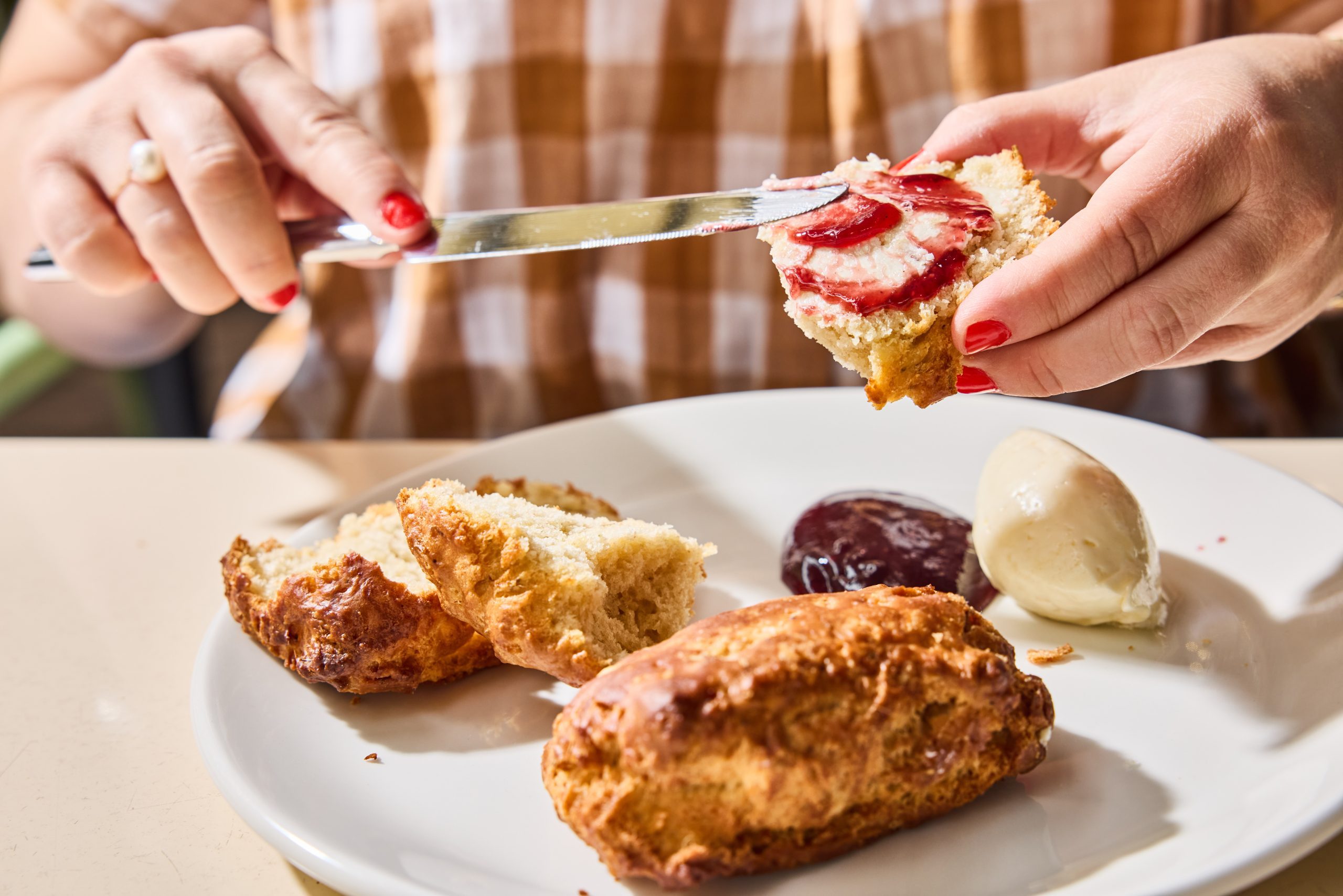 Hands spreading jam on a scone