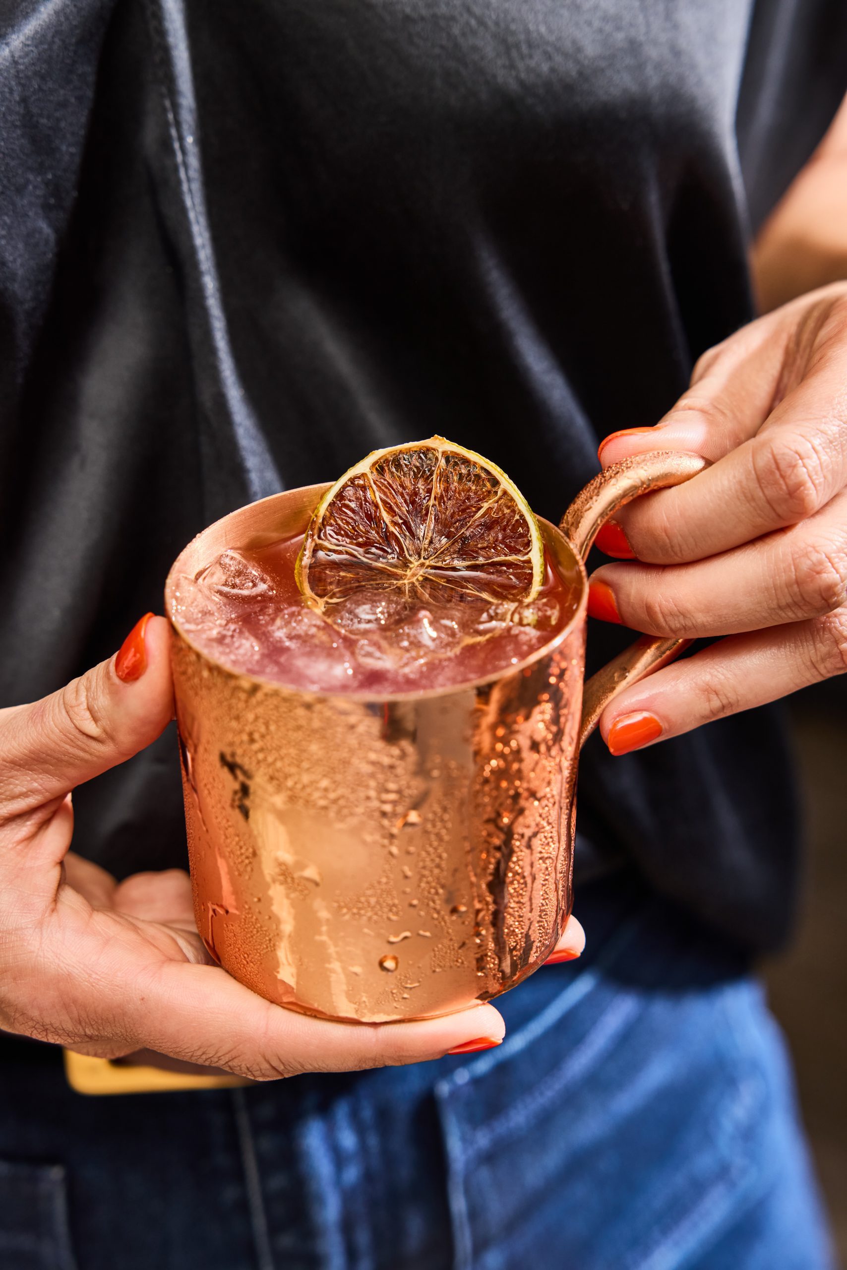 Hands holding a cocktail in a copper mug