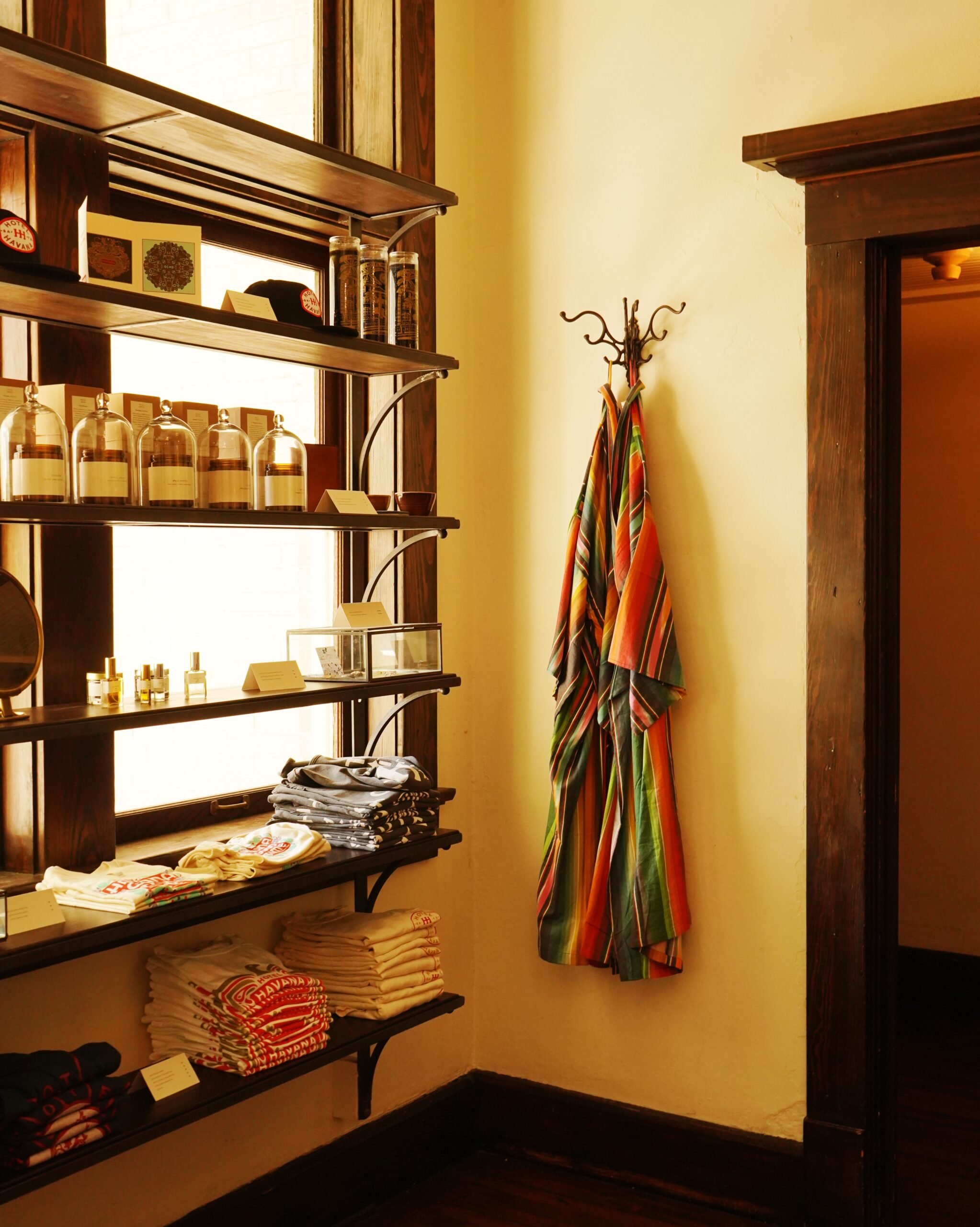 Retail shelves at Hotel Havana featuring candles, shirts, robes on hooks