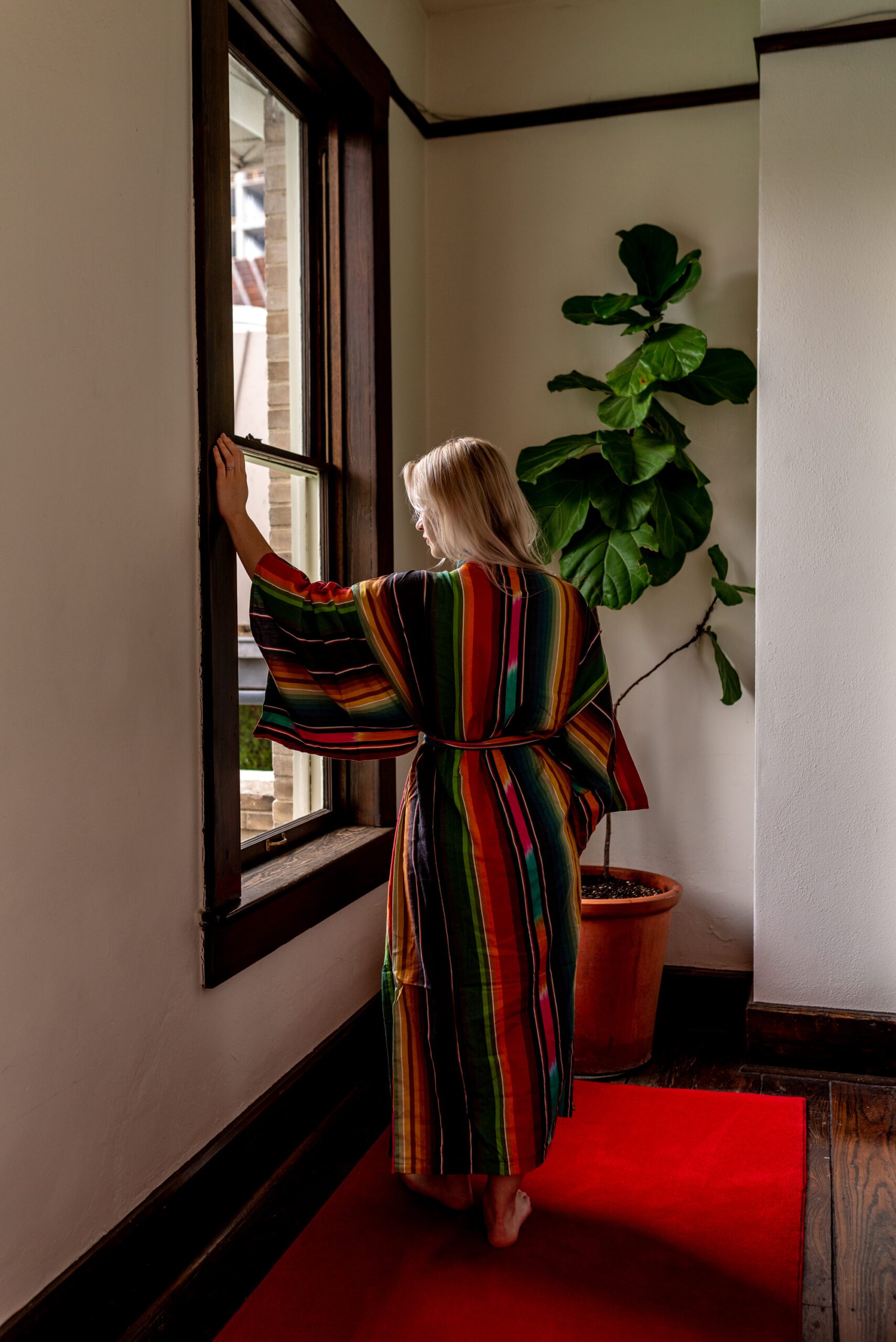 Woman in a robe looking out the window of the hallway of Hotel Havana