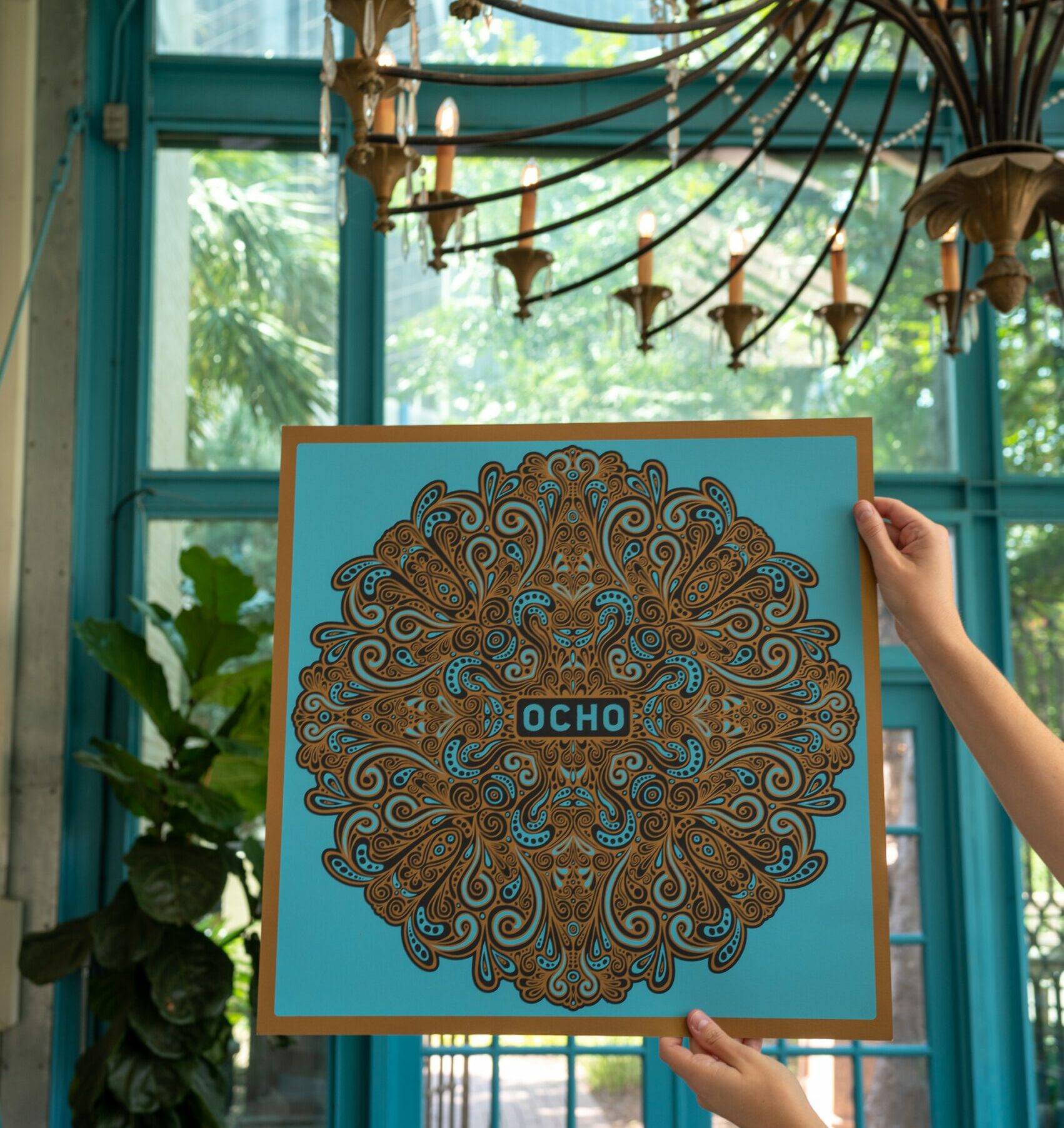 Ocho poster being held by two hands in Ocho