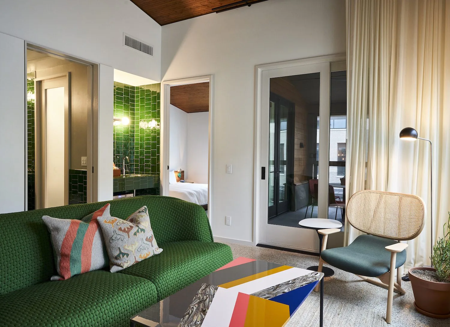 A seating area with a green couch and green subway tiled sink in a Spring Suite room