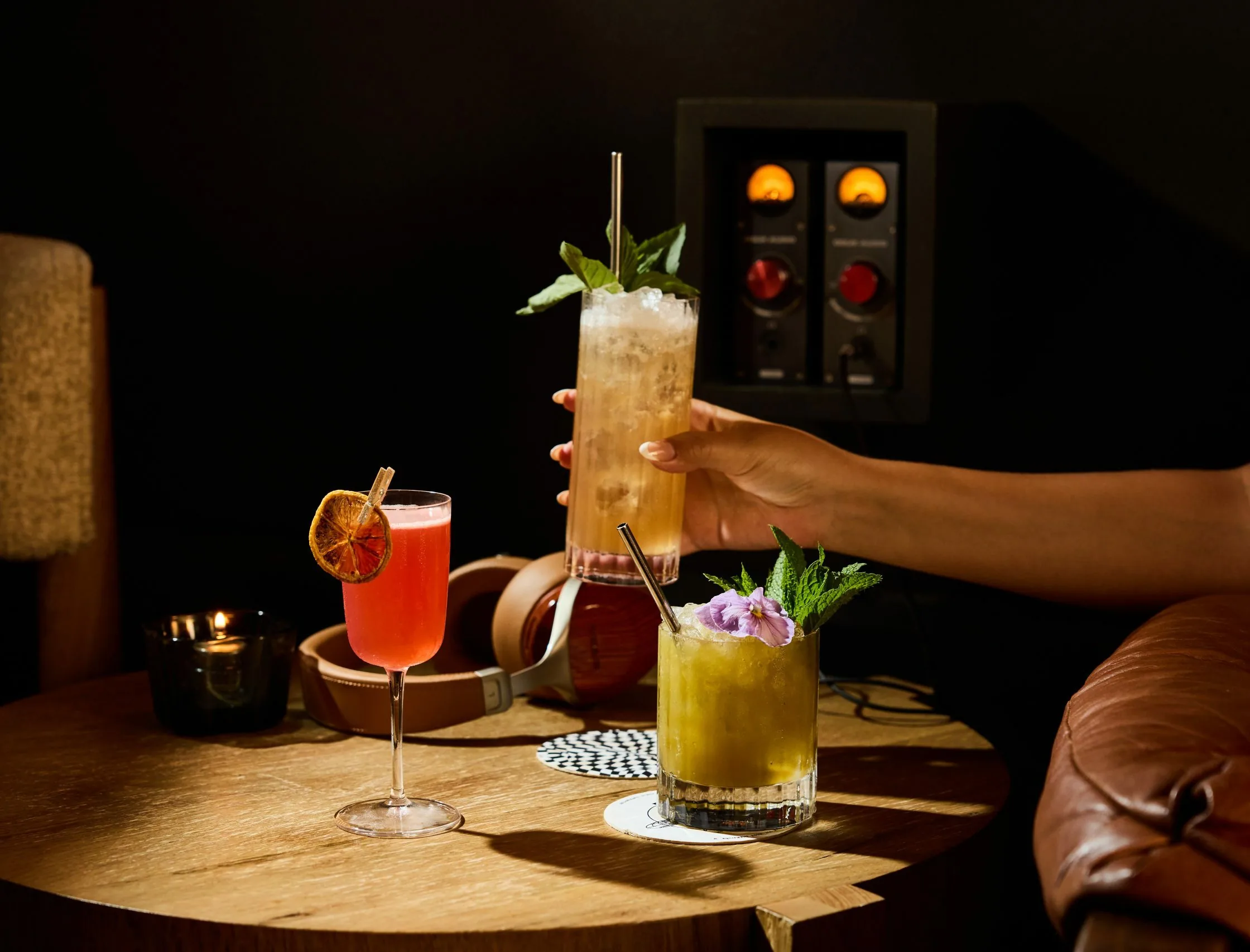 hand holding a cocktail with other cocktails on a table