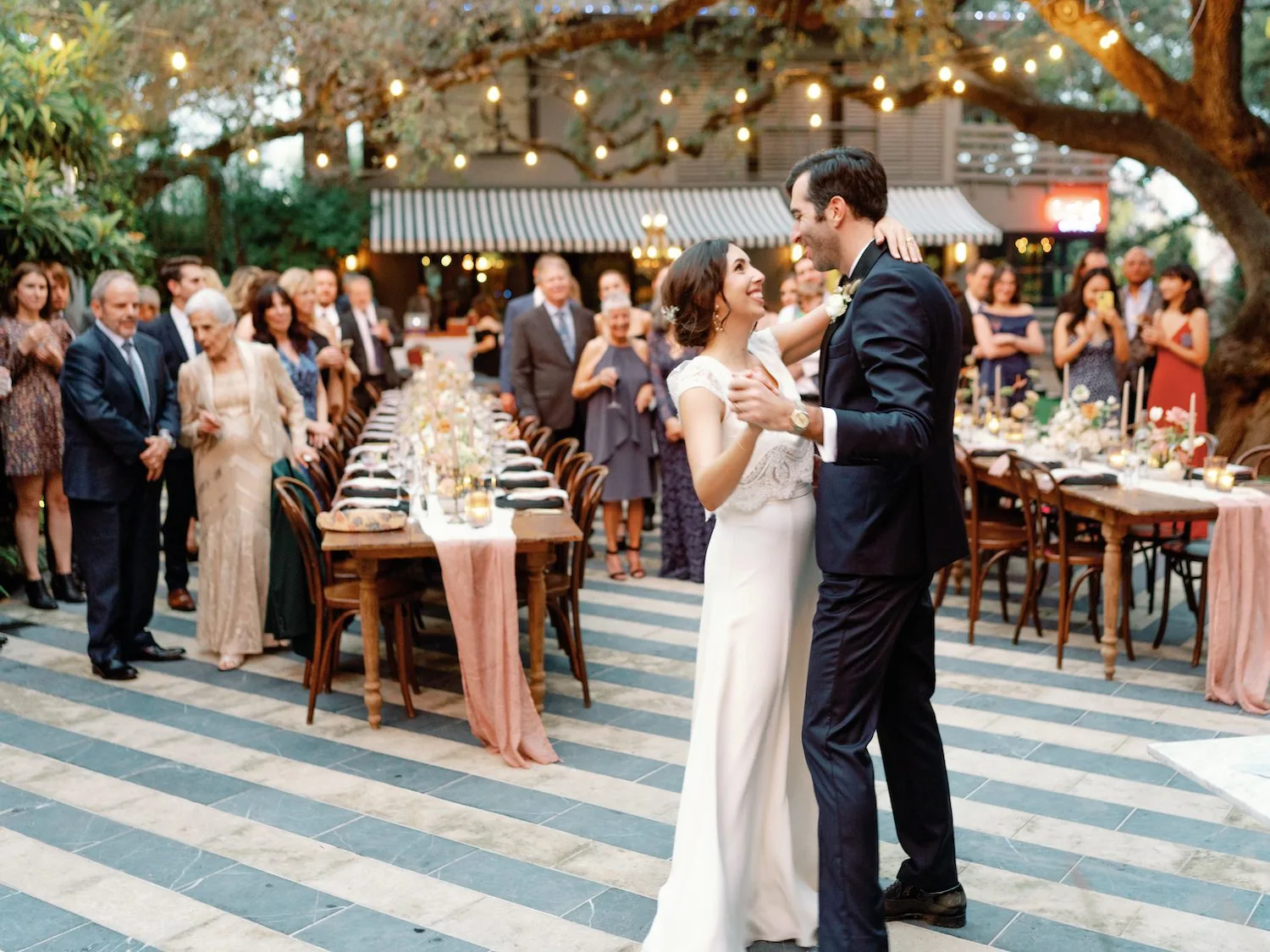 A bride and groom having their first dance in front of their wedding guests in the courtyard