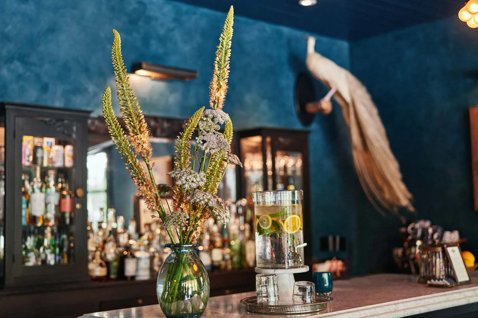 A floral arrangement at the lounge bar with drinks and glasses at Hotel Saint Cecilia