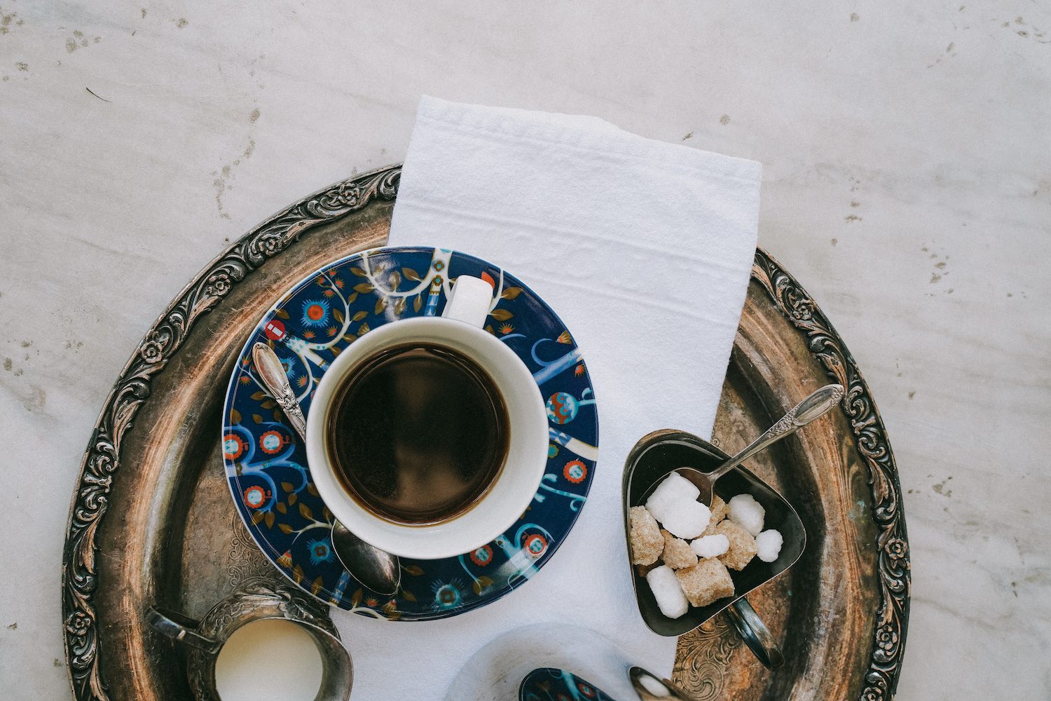 A tray with a coffee cup, sugar cubes, and cream.