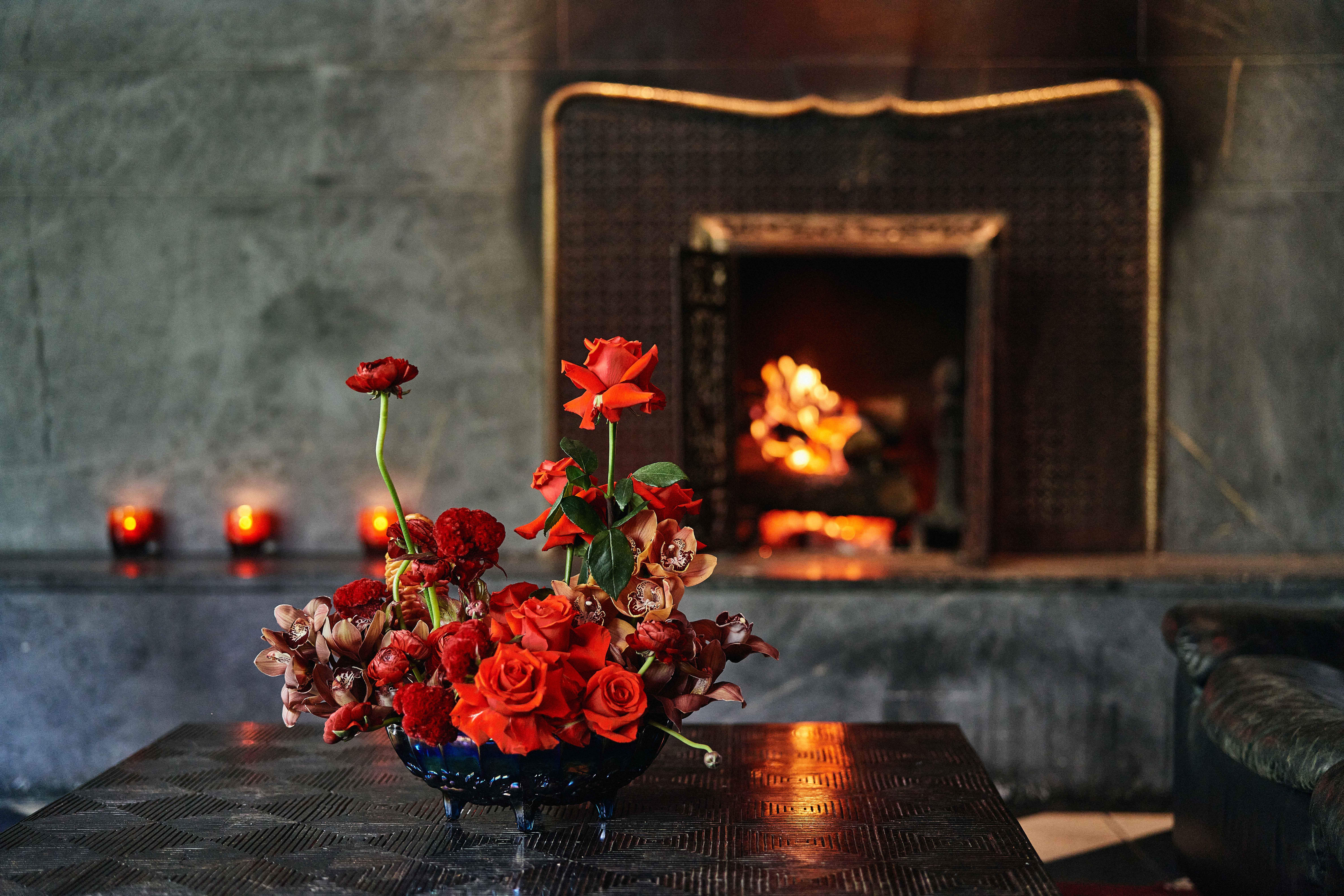A floral arrangement by Antonio Bond sitting on a table in front of the fireplace in the Saint Cecilia lounge