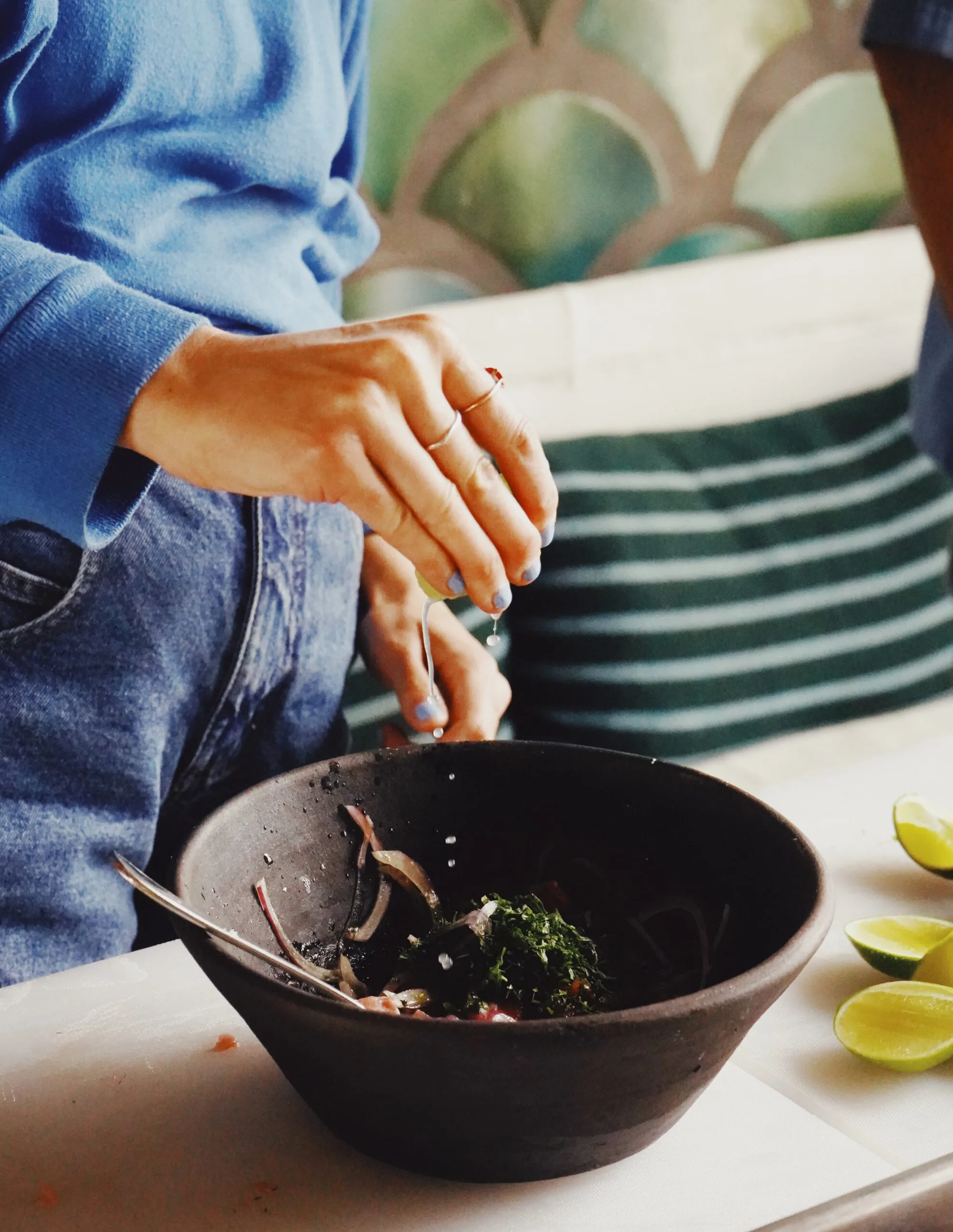 Chef squeezing lime juice into a salad bowl