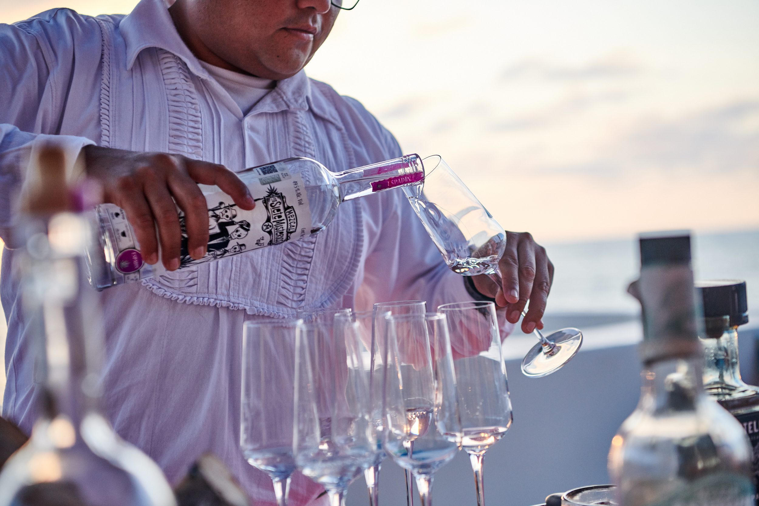 A man pouring glasses of mezcal