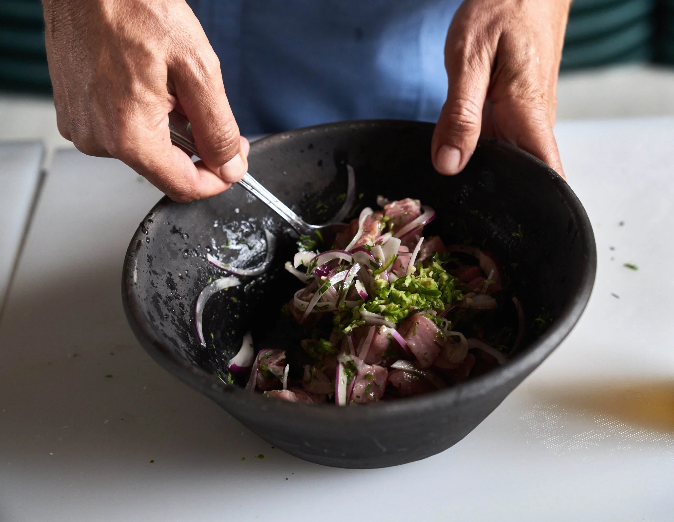 Hands mixing salad in a wooden bowl