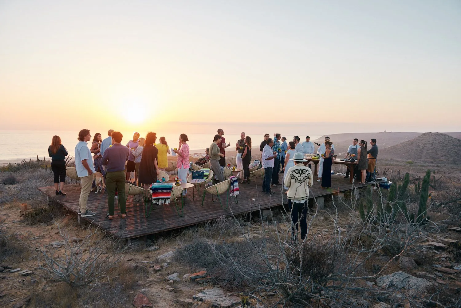A gathering of people on a raised wooden platform at sunset