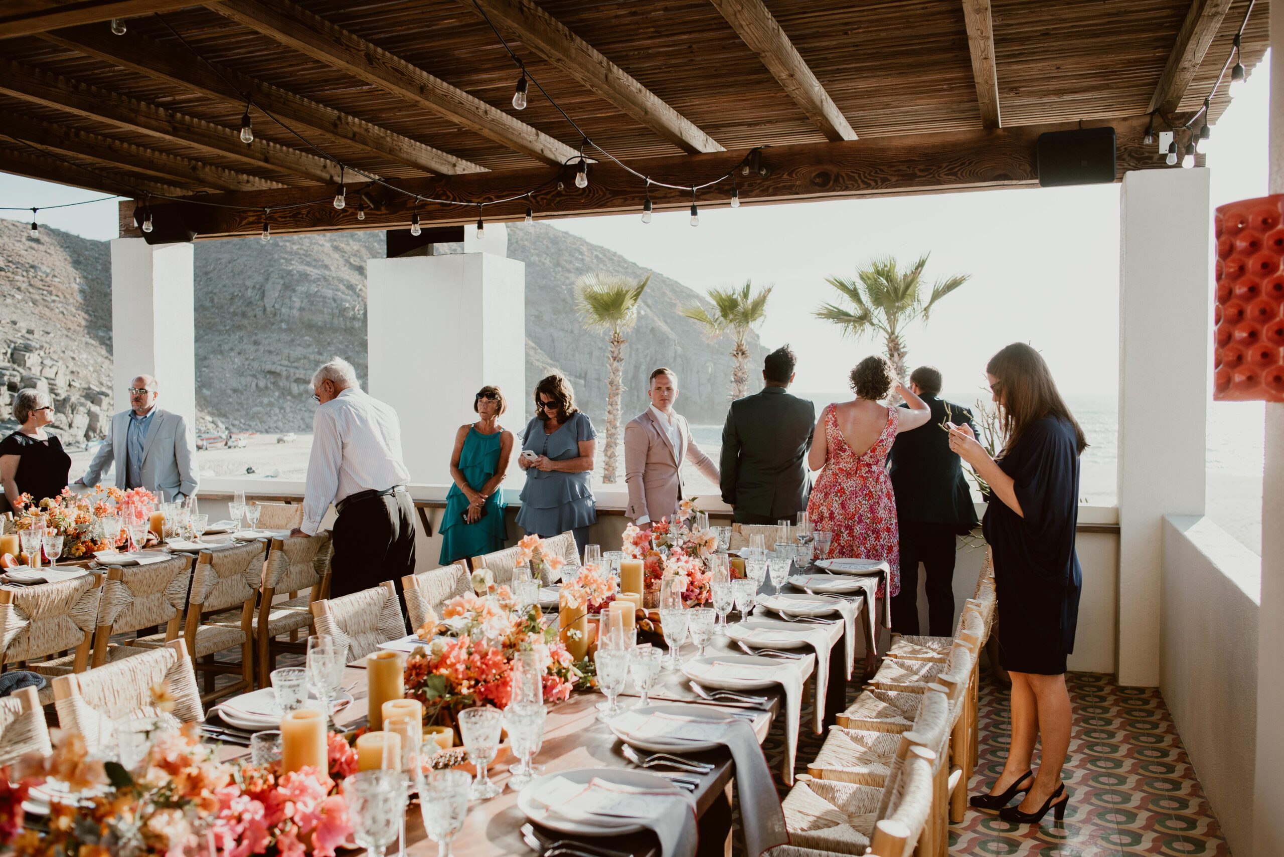 Guests standing around a long table before a wedding dinner