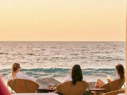 people sitting on chairs looking out at ocean