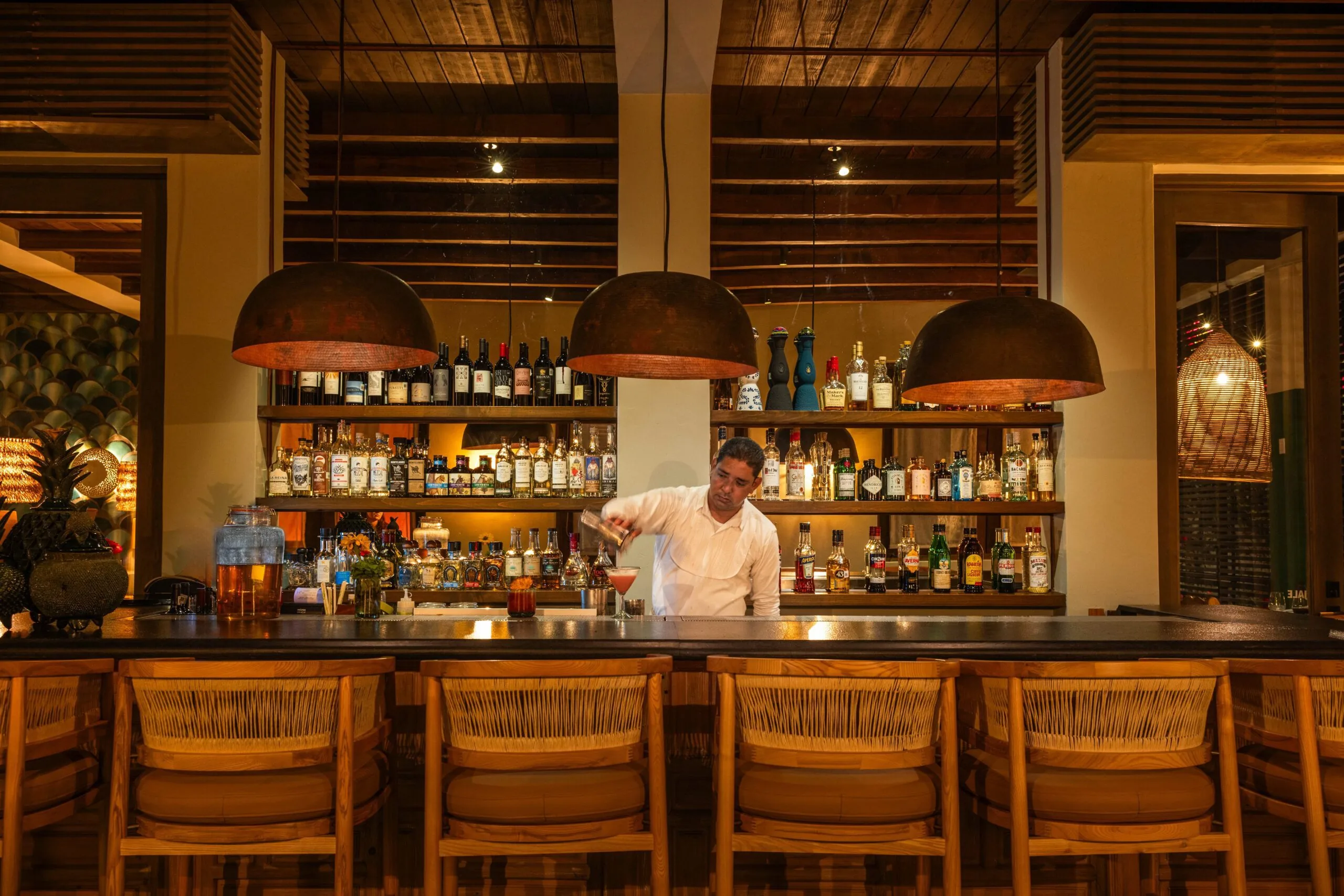 Bar man pouring a cocktail at a bar