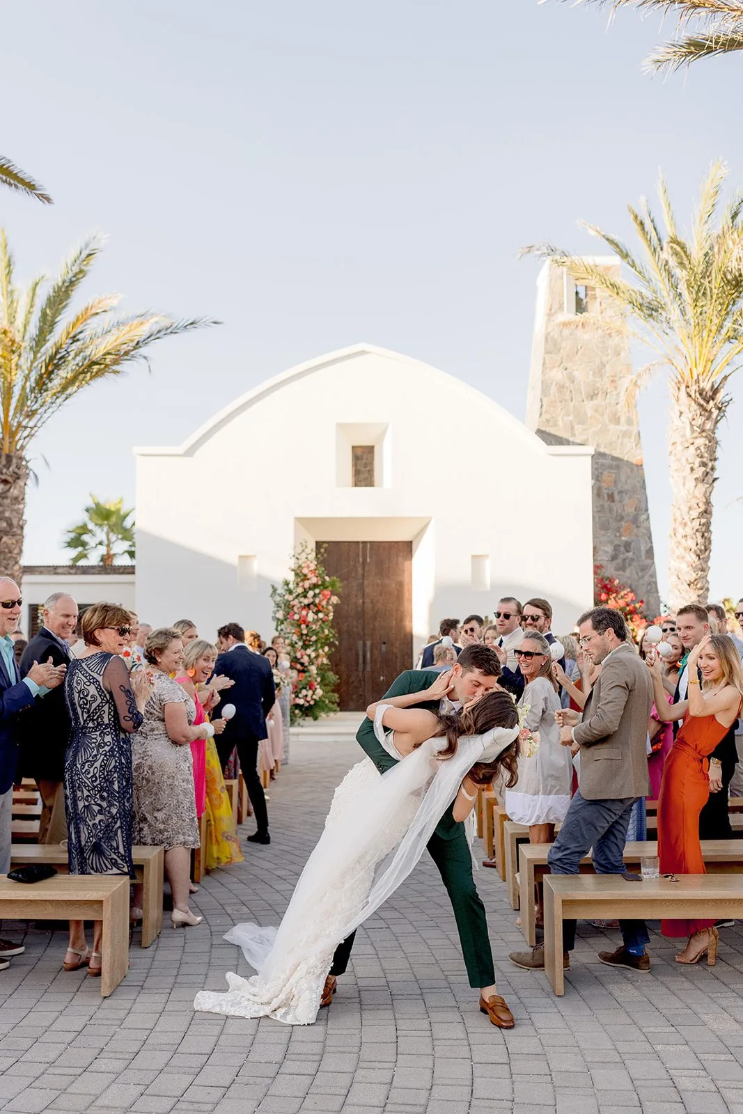 A bride and groom embracing in front of their guests