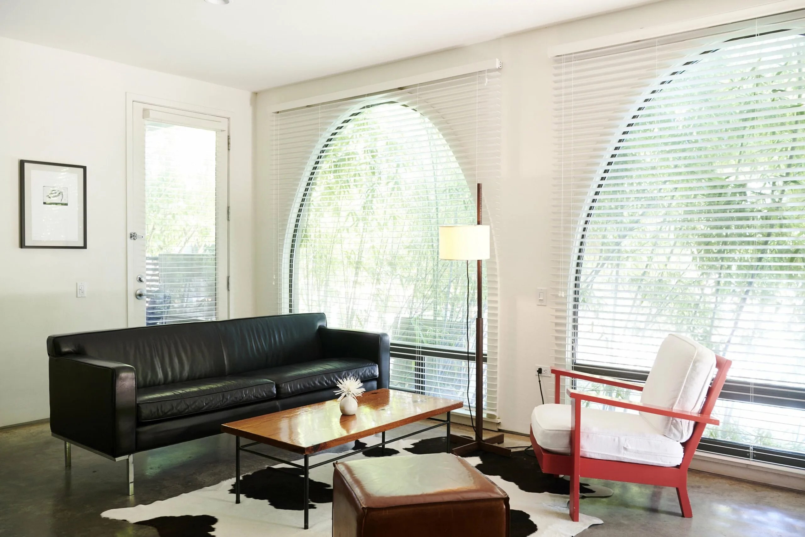 Interior of the Courtyard Suite, Room 40 with a black leather sofa, red and white chair and large arched windows