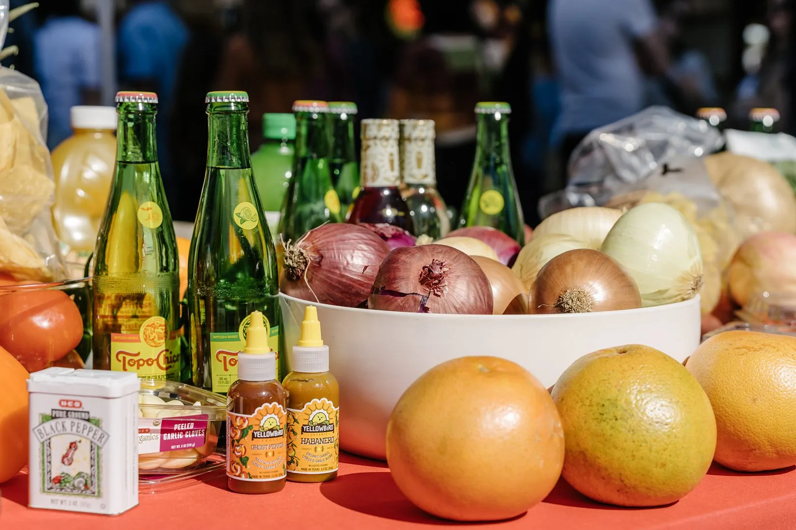 A table of onions, oranges, hot sauce and drinks