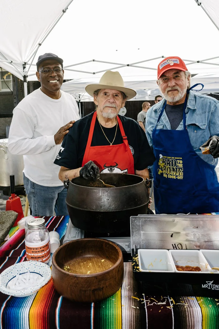 Three chefs standing around a pot of chilli