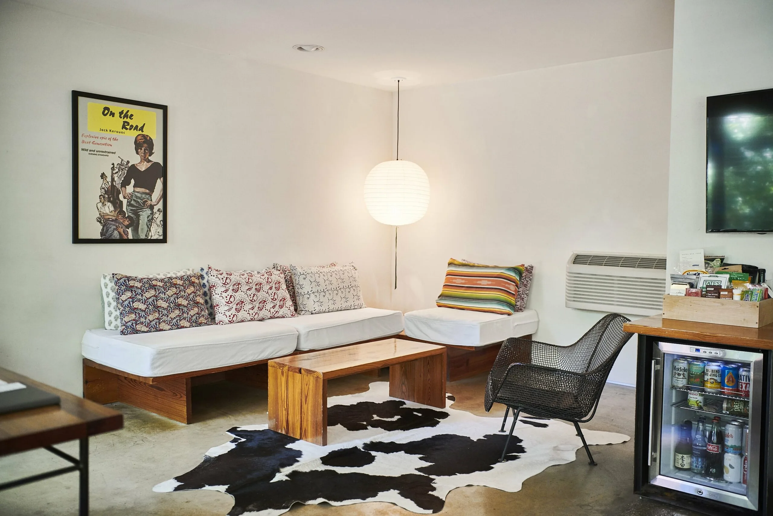 Room 33 lounge area featuring an L-shaped couch, black wire chair, and cow hide rug