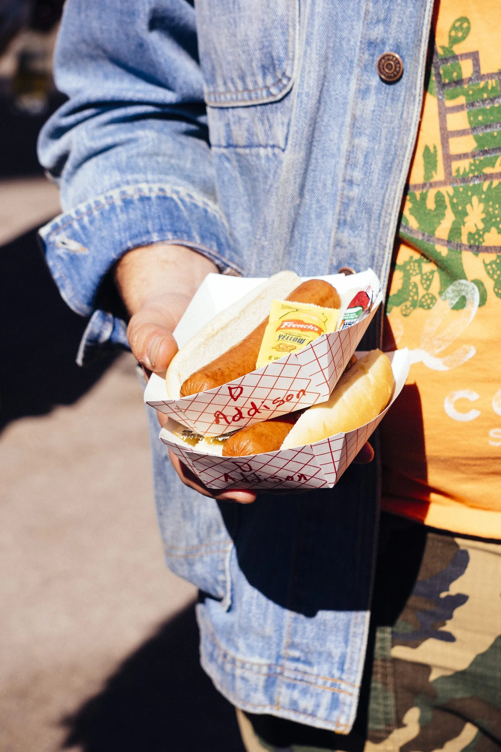 A hand holding two trays of hot dogs