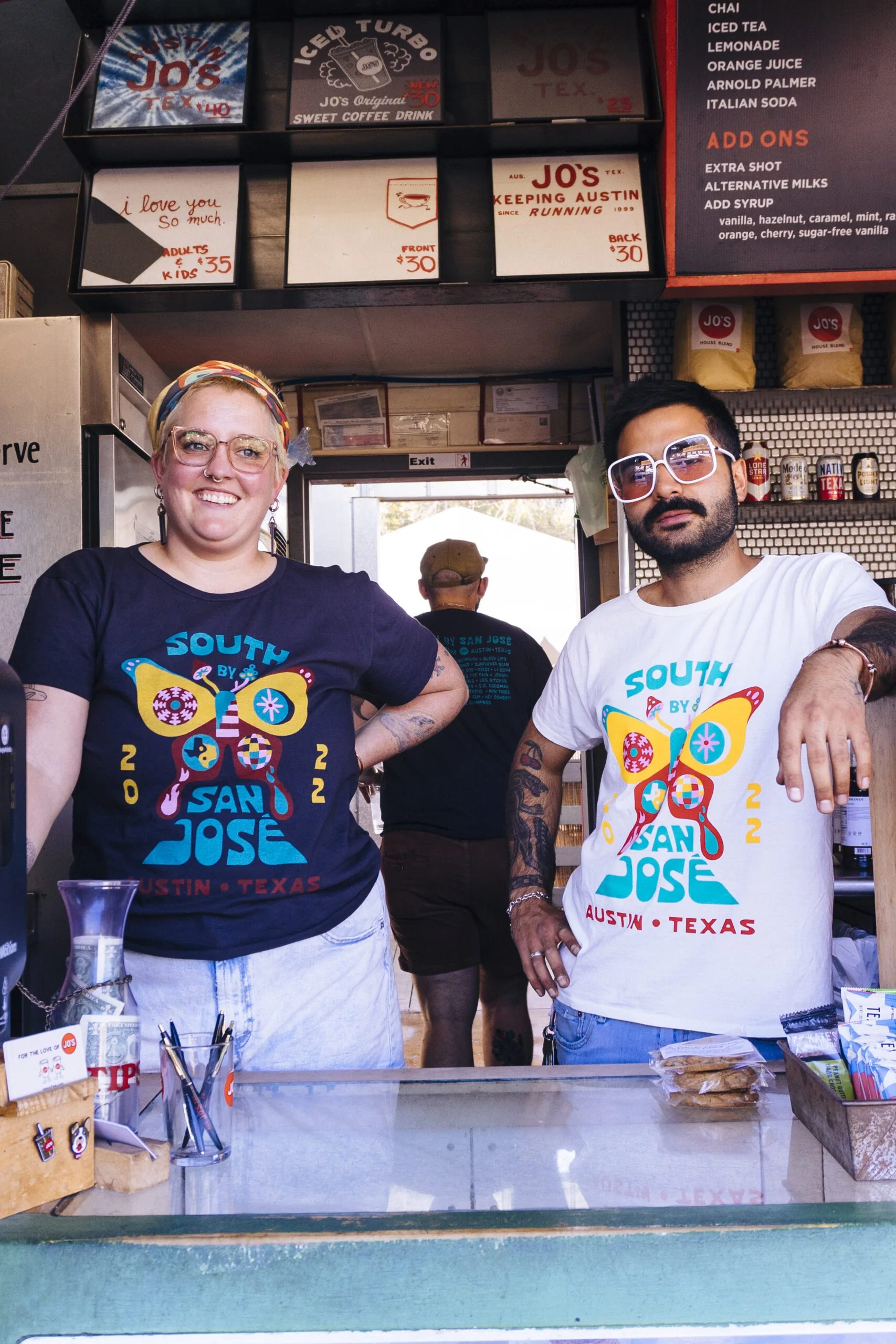 Two food vendors posing behind a counter