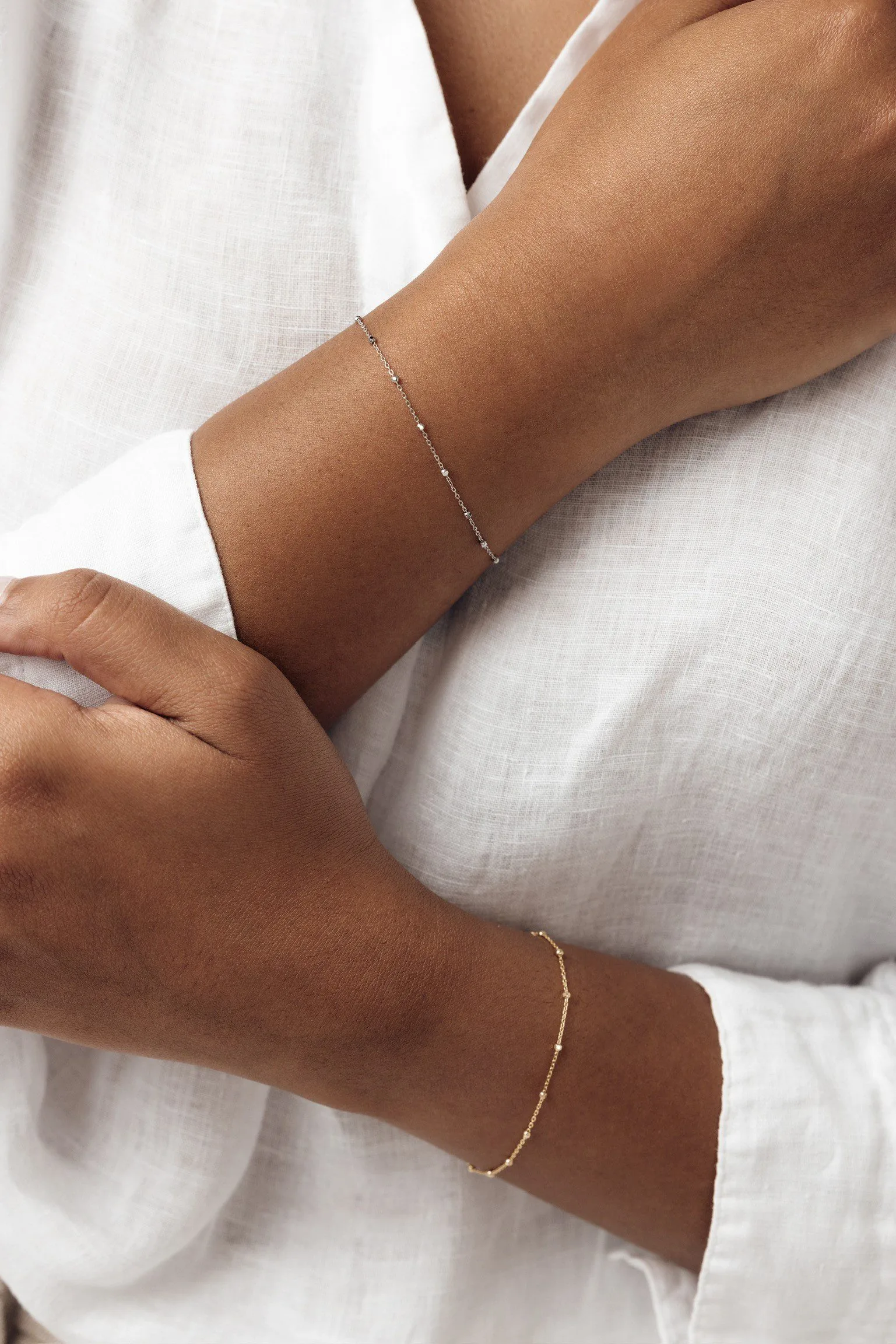 person's arms with bracelet on each