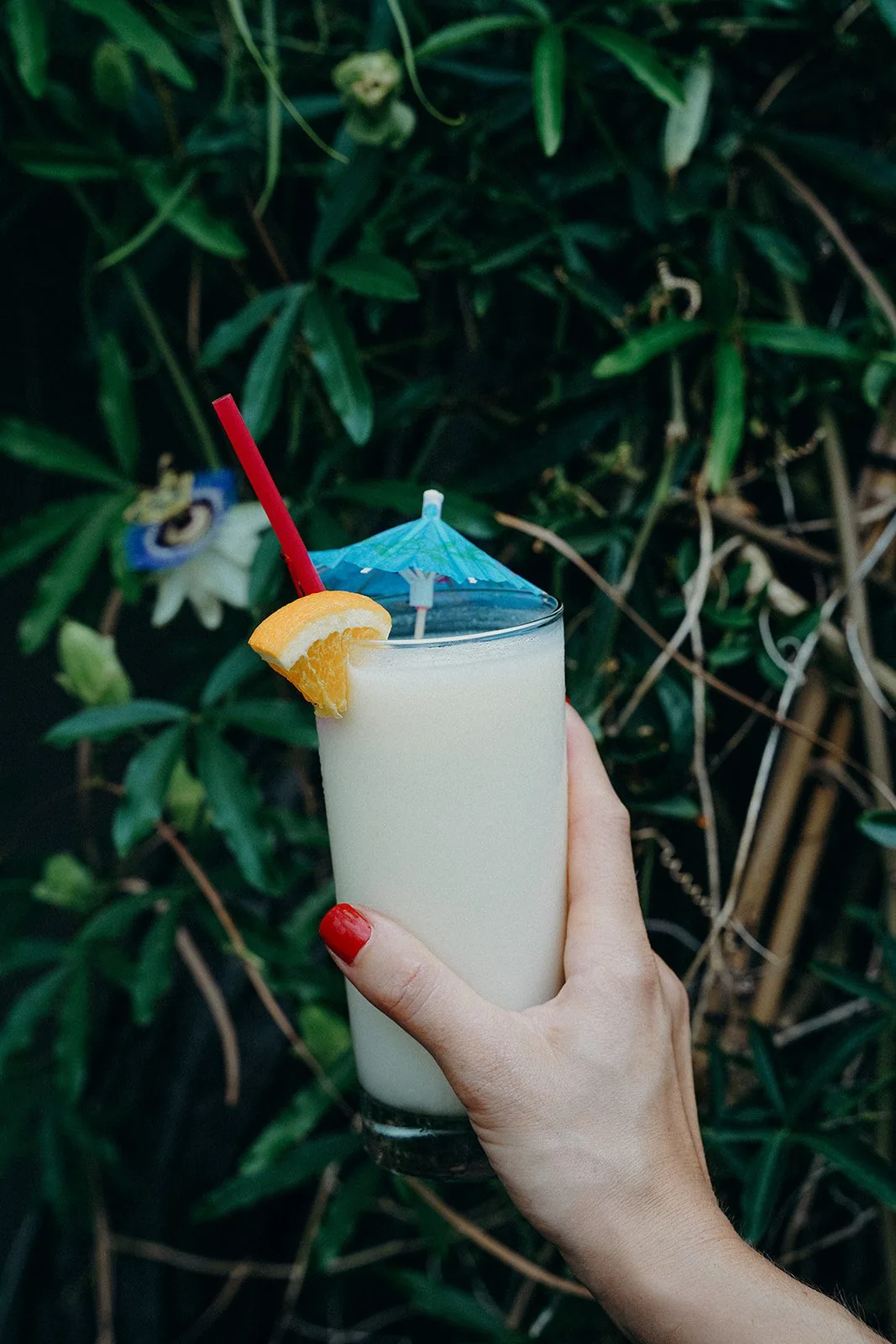 A white tropical cocktail with a blue cocktail umbrella