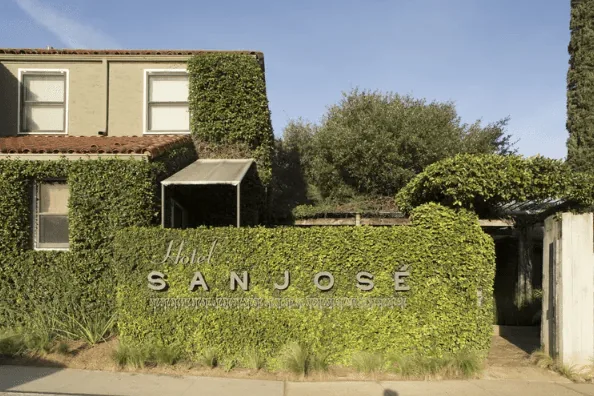 Exterior of Hotel San Jose with sign surrounded by ivy
