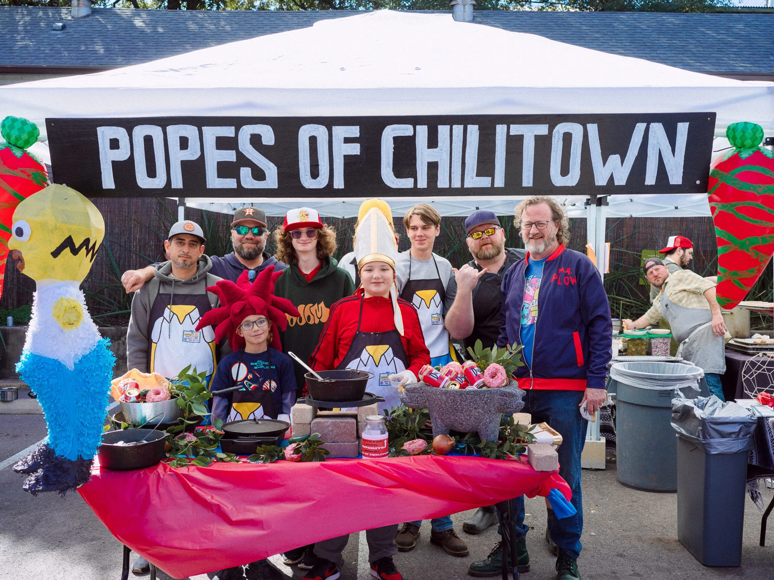 "Popes of Chilitown" sign. Group of people posing for photo