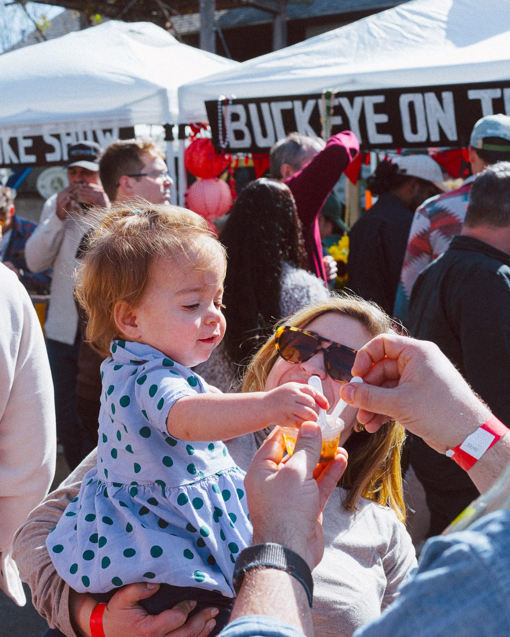 woman holding child who is trying the chilli sample