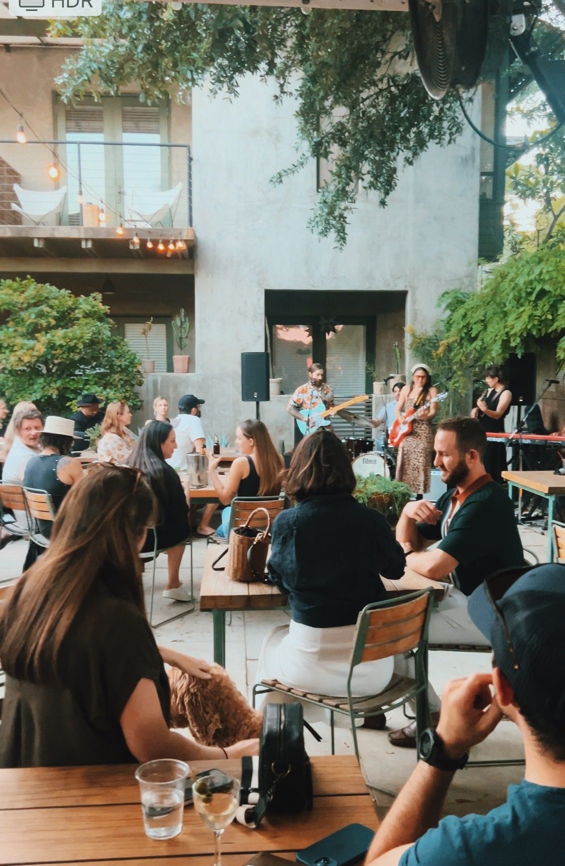 group of people outside seated at tables listening to live band