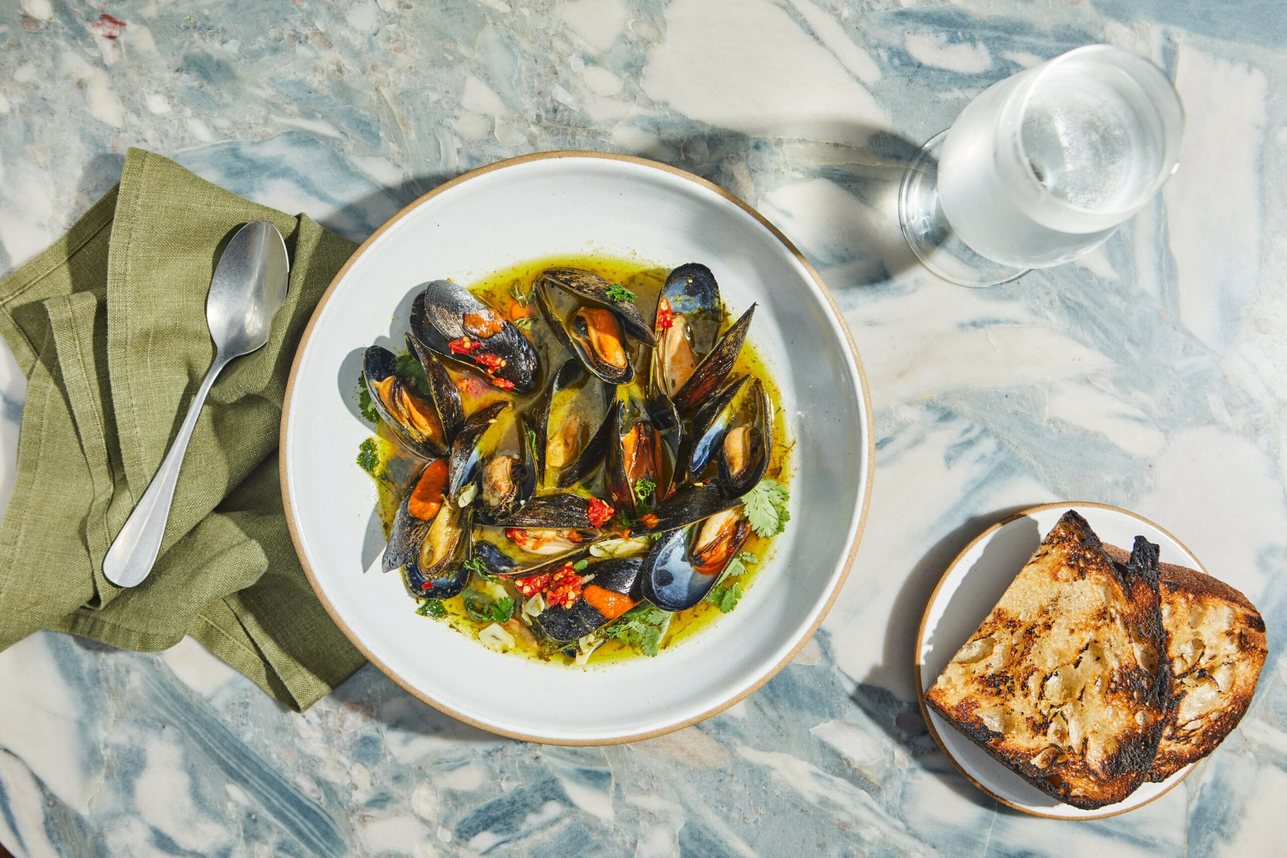 PEI Mussels with white wine herbed butter sauce, grilled seeded sourdough, summer house hot sauce