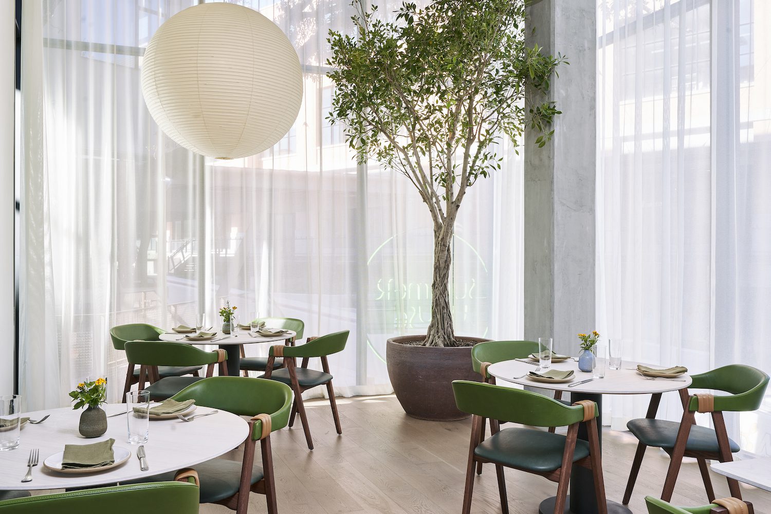 Tables positioned in front of large windows at Summer On Music Lane