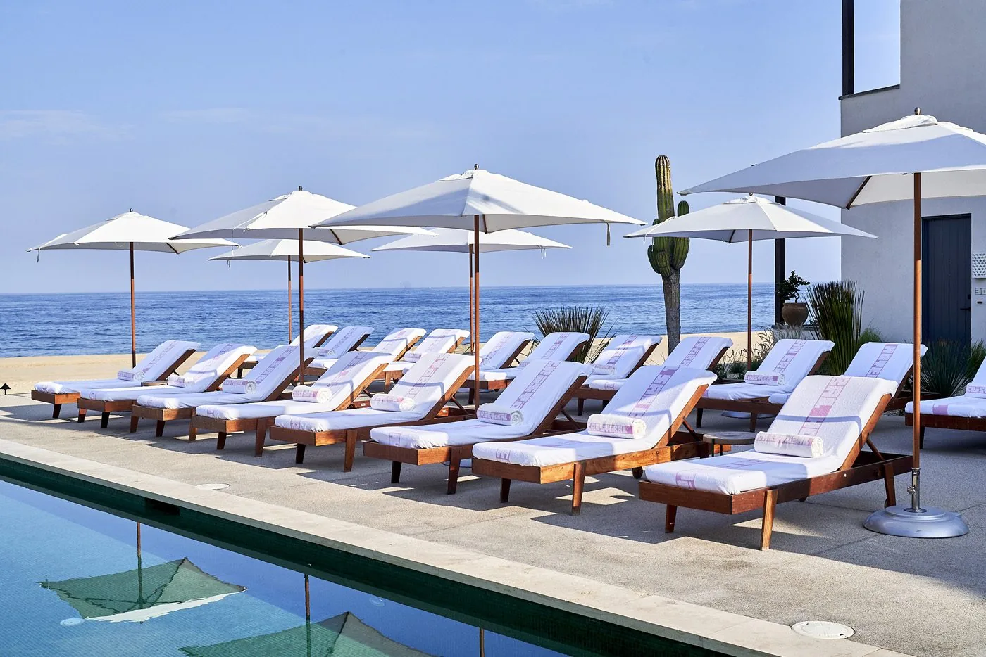 outdoor pool with white chairs and umbrellas