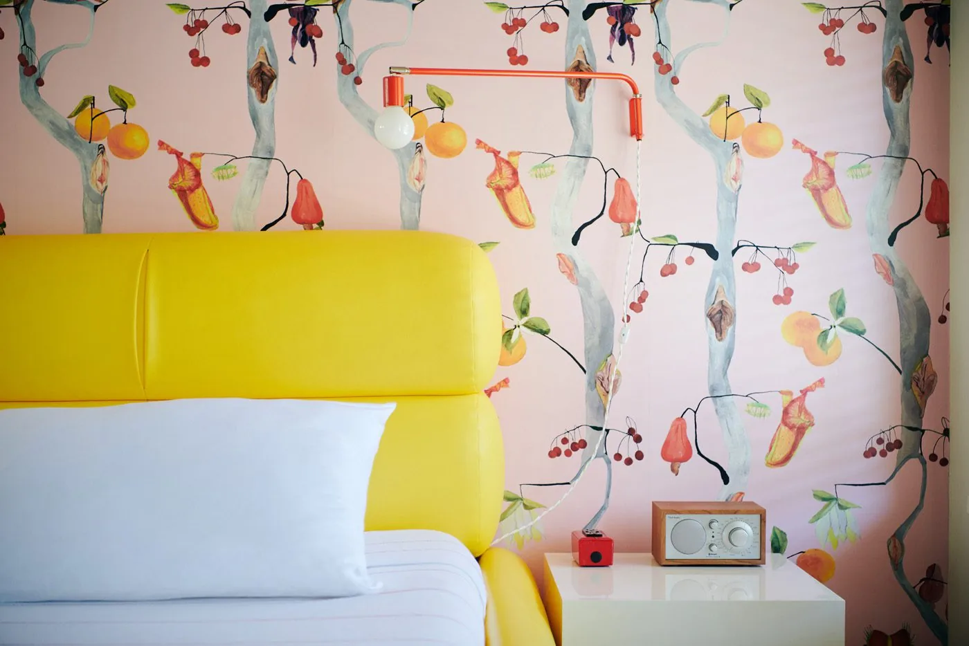 Tight shot of a Deluxe King Room at Austin Motel, featuring bold floral wallpaper and a lemon leather upholstered bed