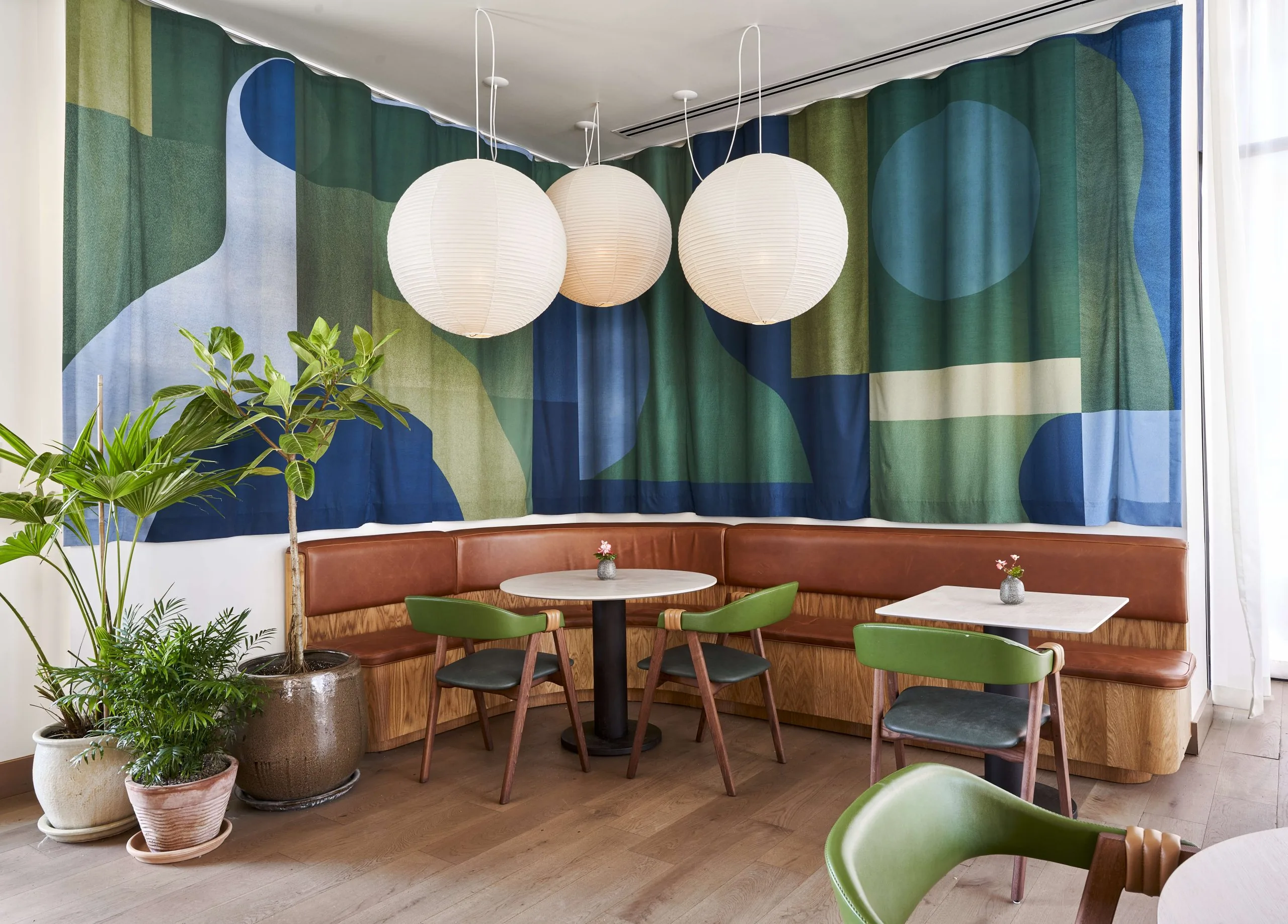The corner booth at Summer House on Music Lane featuring a blue and green tapestry