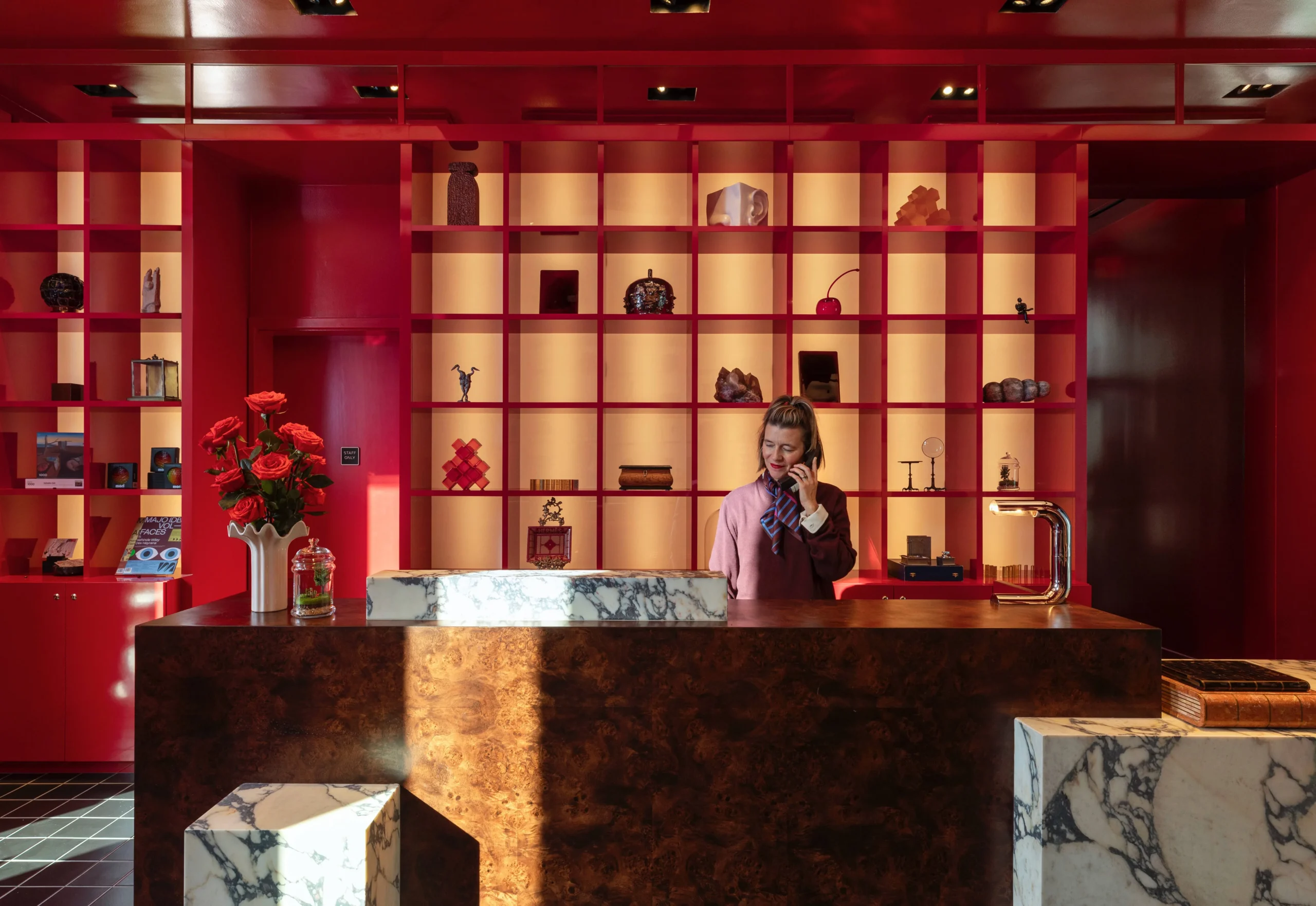 Woman in a burgundy sweater working in front of a red bookcase