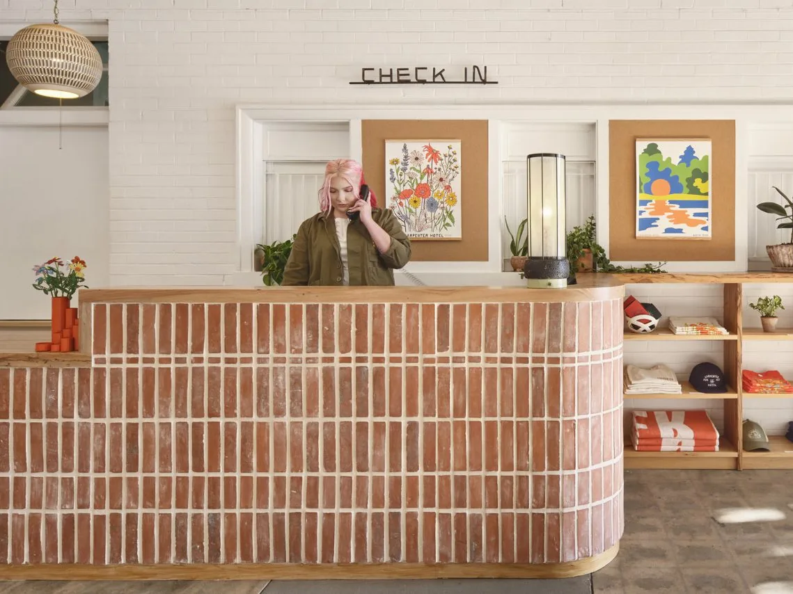 Woman with pink hair answering the phone at a brick front desk
