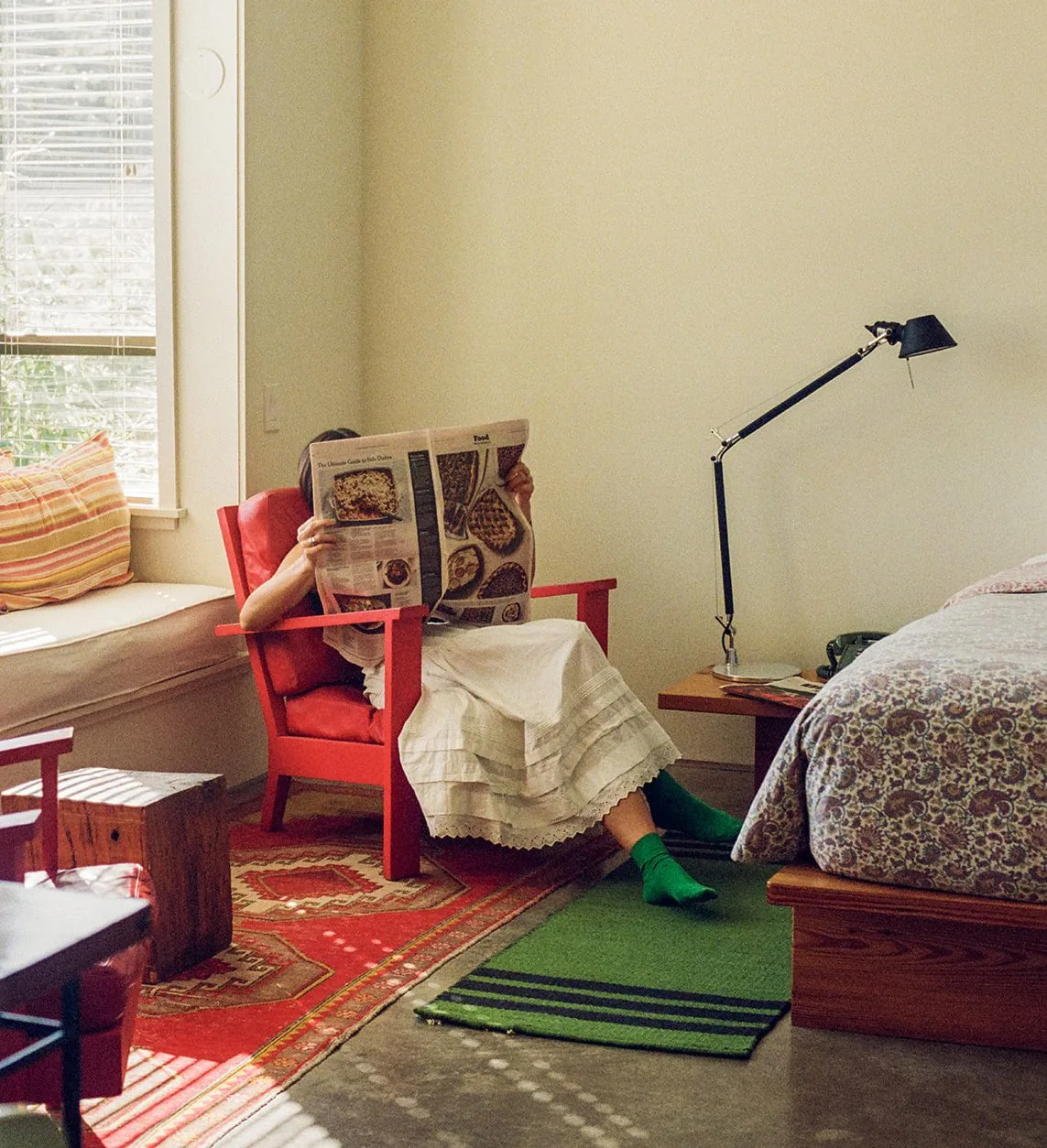 Woman reading a newspaper in a bright red chair