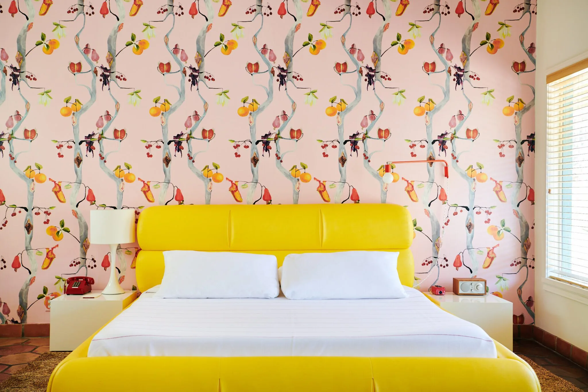Wallpapered bedroom with yellow leather bed at Austin Motel
