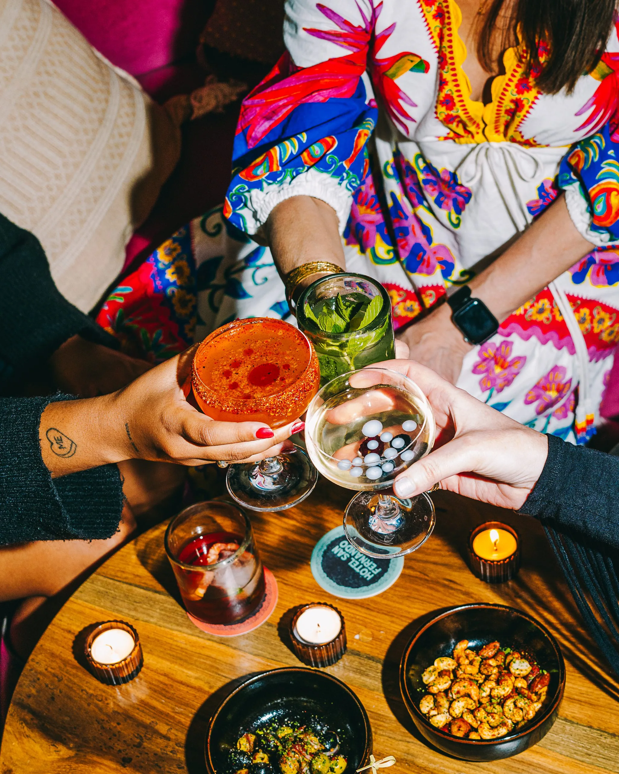 Hands holding cocktails in a dimly lit bar