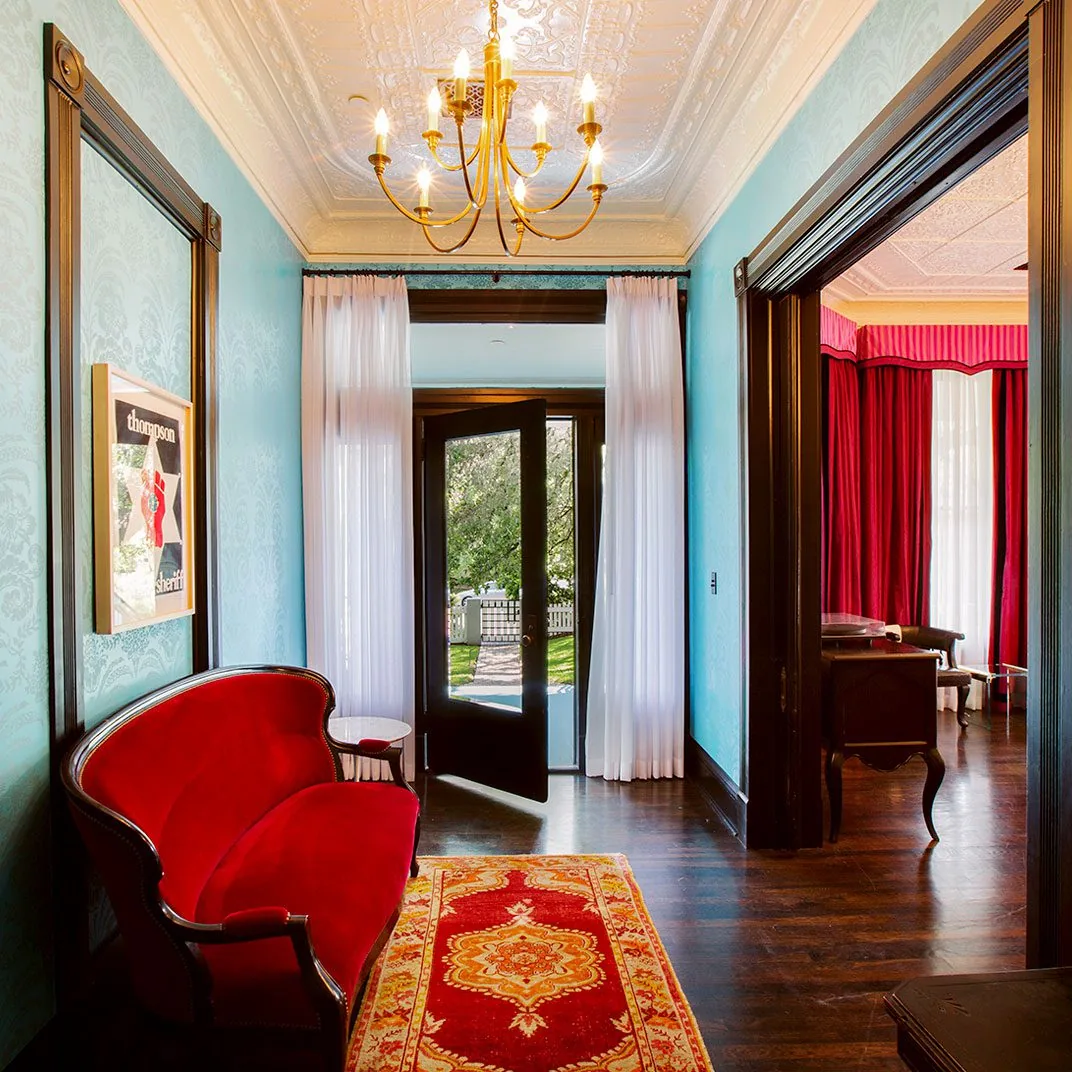 View of one of the Suites at Hotel Saint Cecilia, red velvet couch, chandelier, peacock blue walls