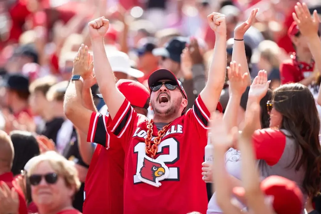 Louisville fan celebrating with his arms raised