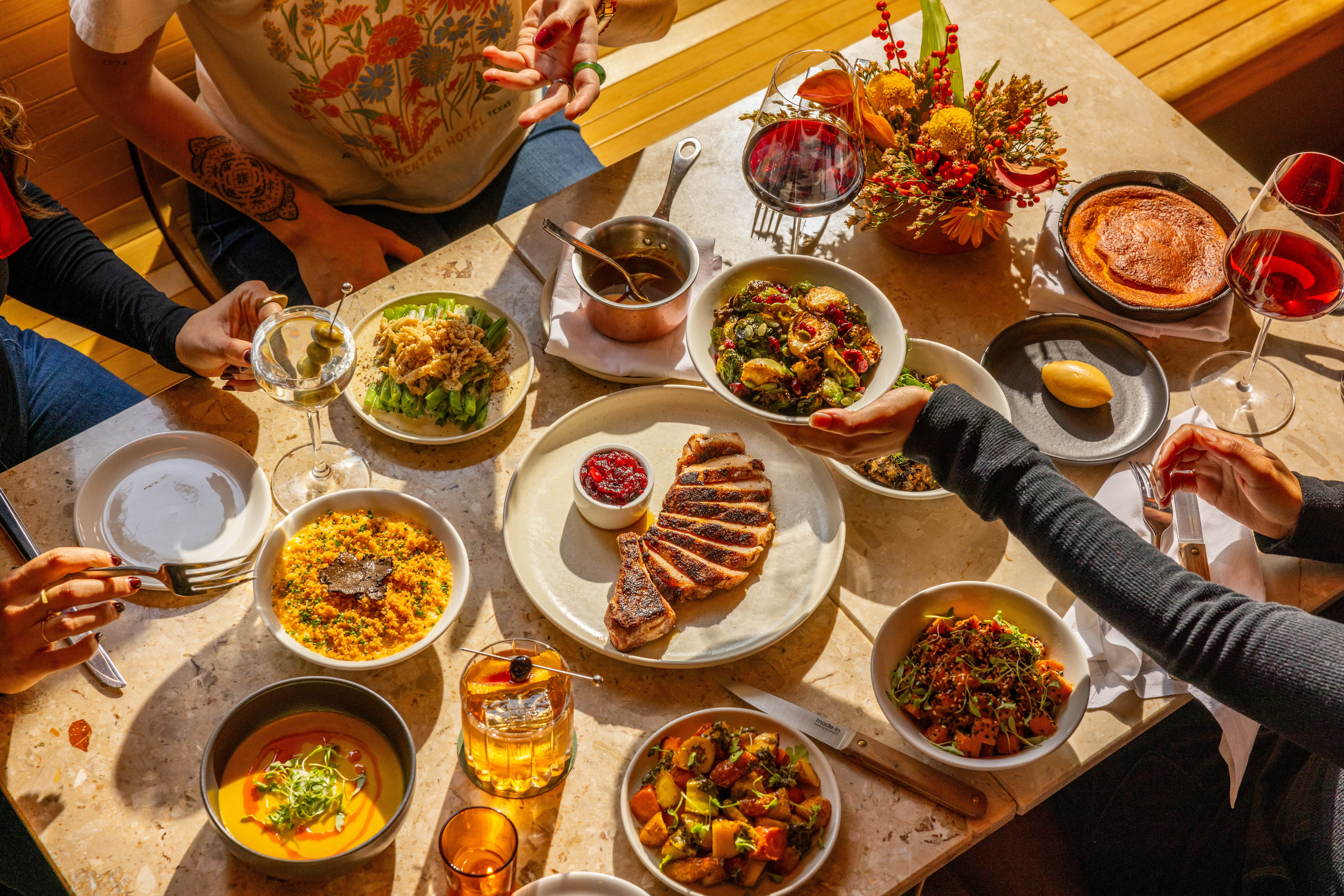 Spread of Thanksgiving food from above with hands passing dishes around